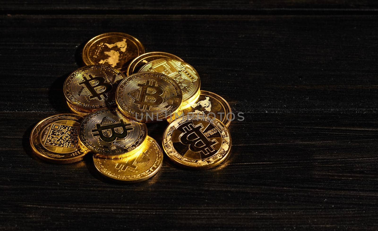 Leader in cryptocurrency bitcoin BTC on a top of coins against black wooden surface. Closeup golden coin with bitcoin logo. Stack of decentralized digital currency. Crypto payment. Electronic money