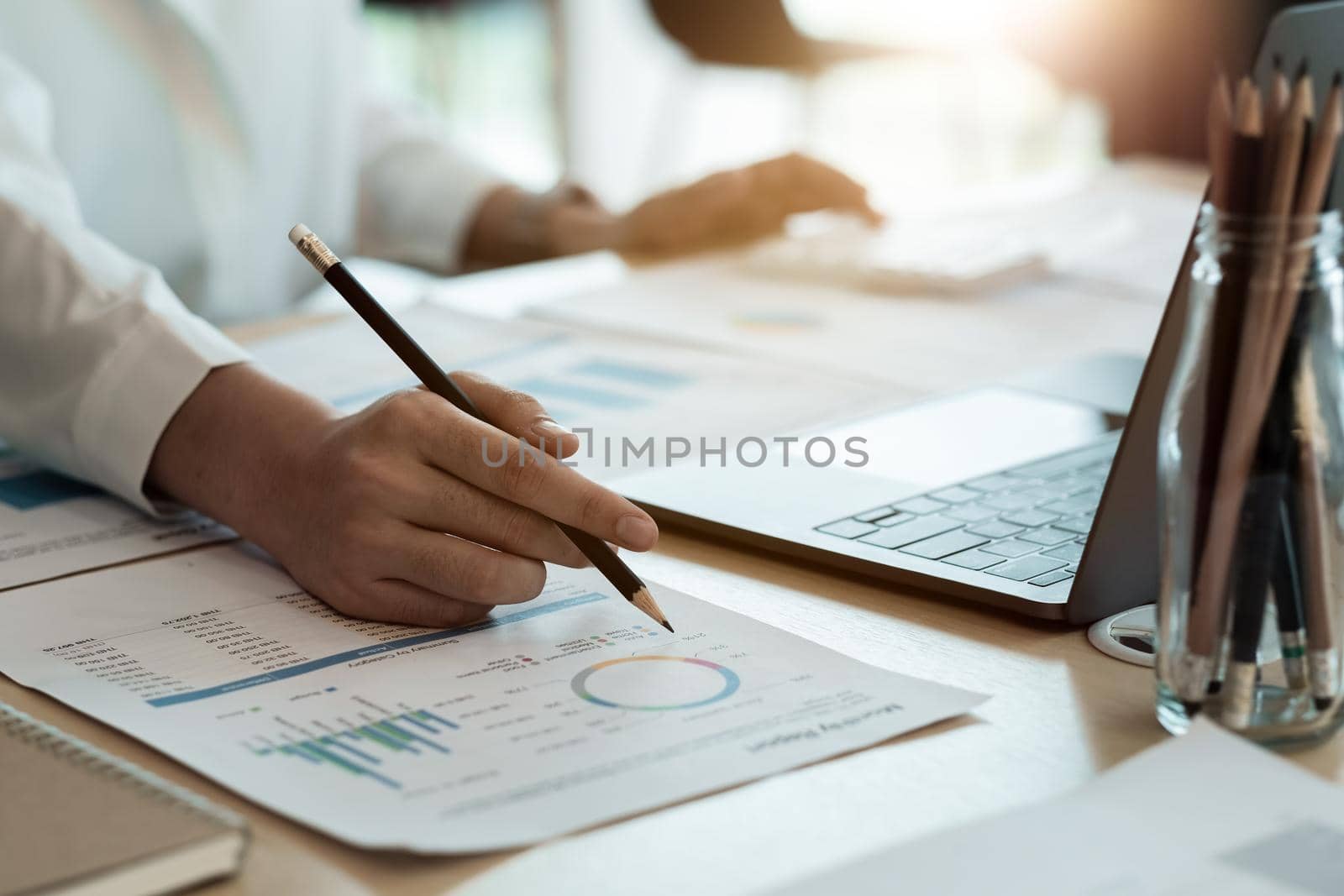 Close up of businesswoman or accountant hand holding pen working on calculator to calculate business data, accountancy document and laptop computer at office, business concept by nateemee