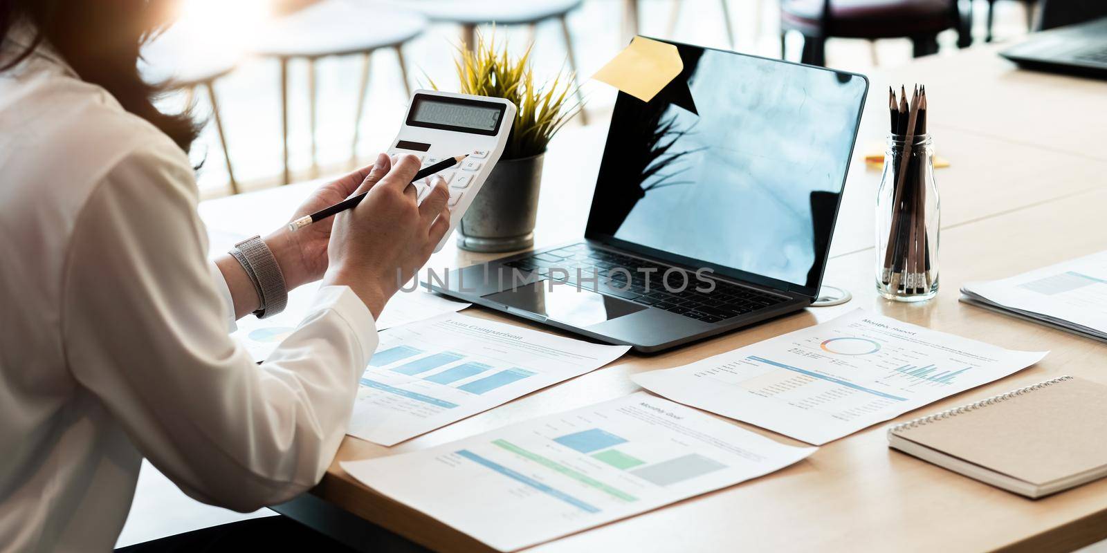 businesswoman working on desk office with using a calculator to calculate the numbers, finance accounting concept. by nateemee