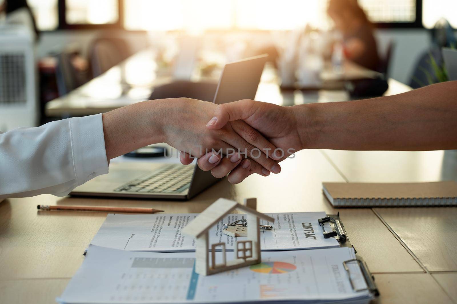 Handshake a successful real estate transaction in an office. Business people shake hands after signing a house purchase agreement. by nateemee