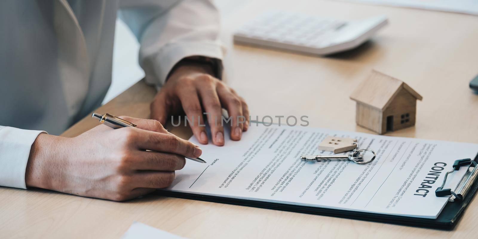 close-up view hands of businesswoman signing leasing home documents and have a apartment keys on paperwork.