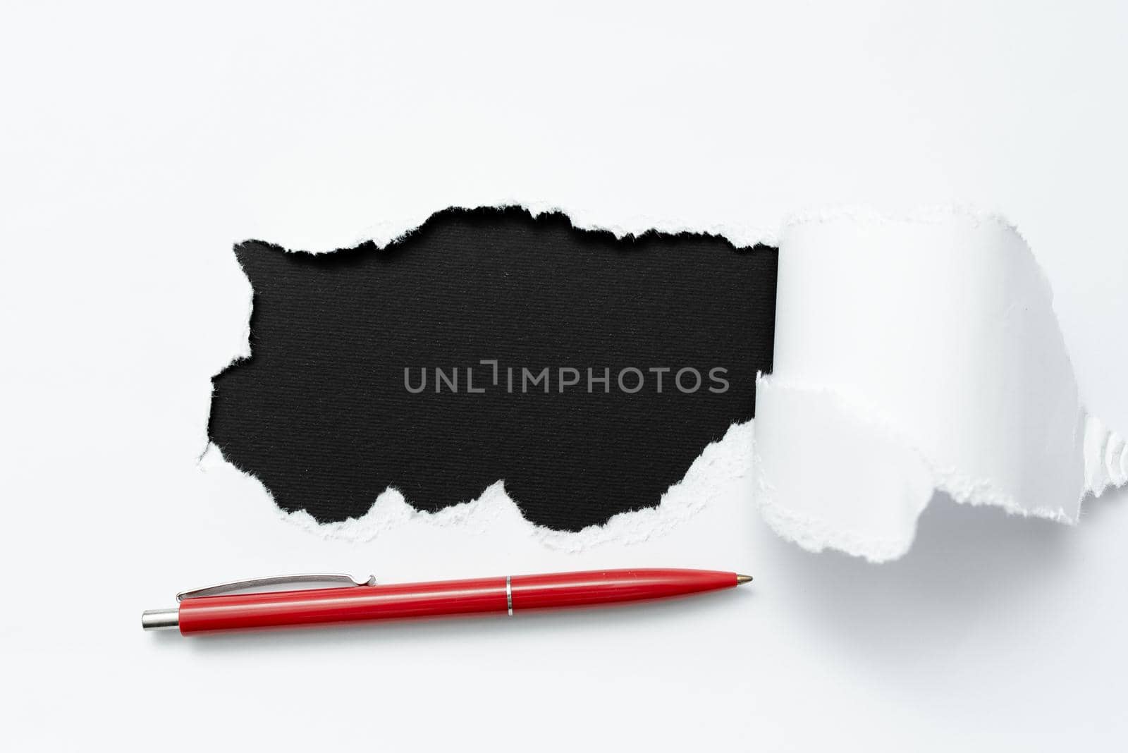 Tear on sheet reveals background with pen on board