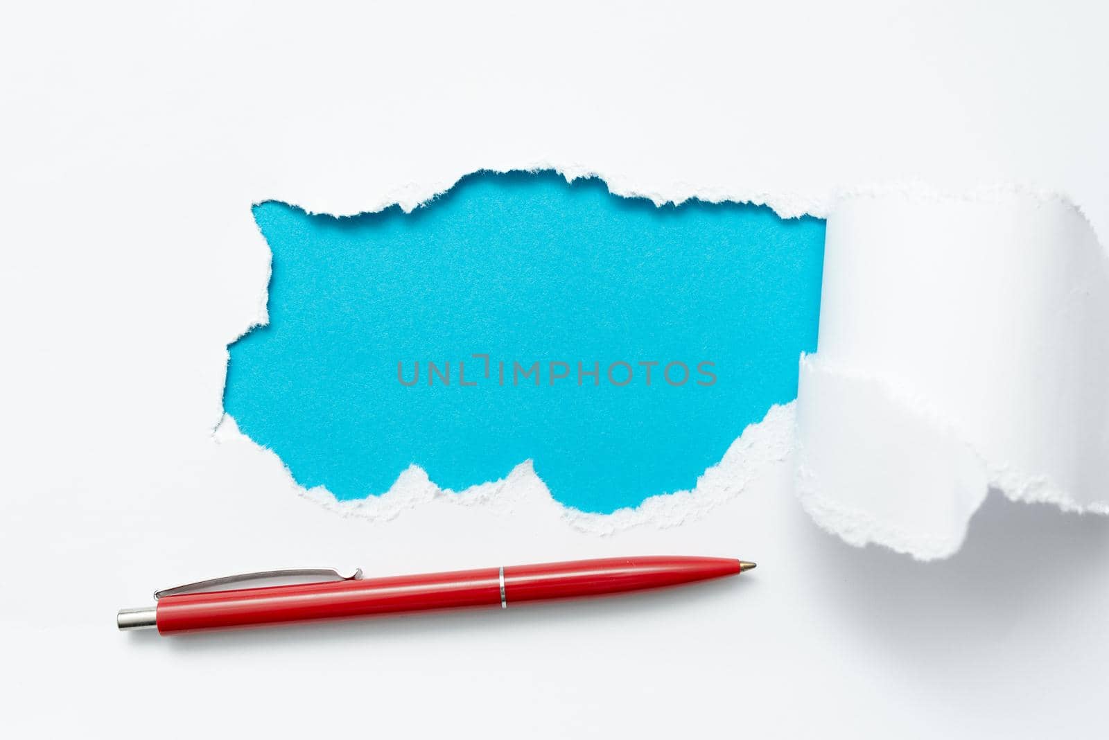 Tear on sheet reveals background with pen on board