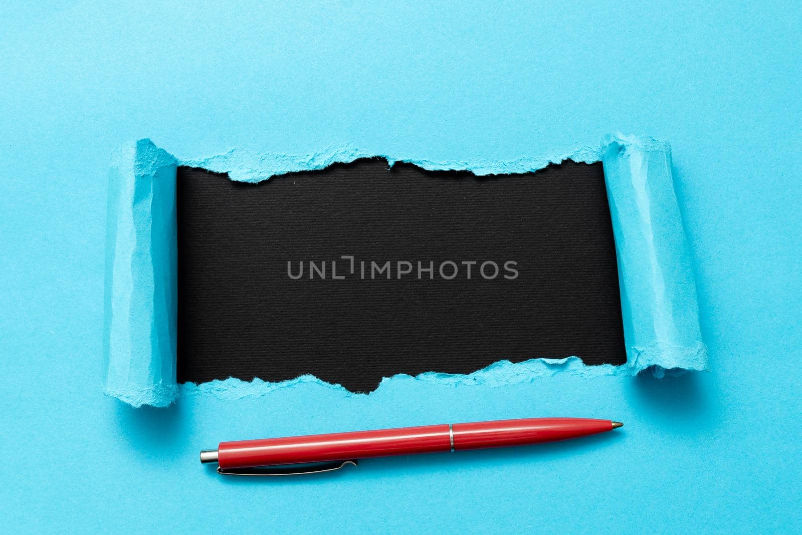 Tear on sheet reveals background with pen on board