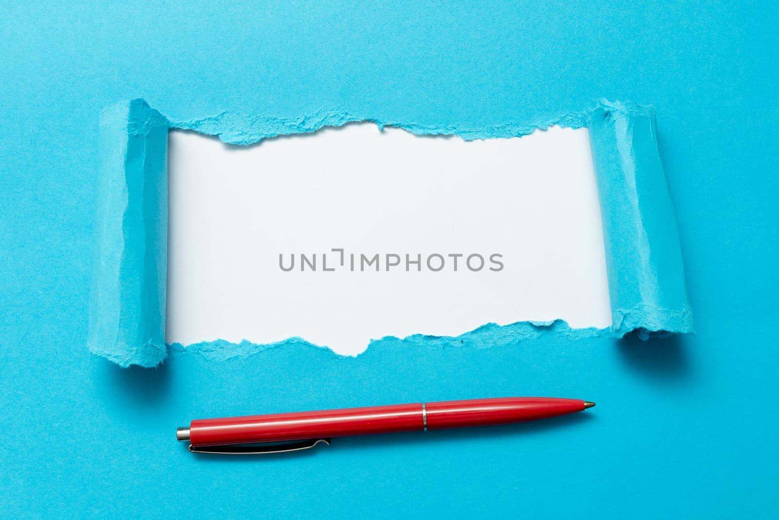 Tear on sheet reveals background with pen on board