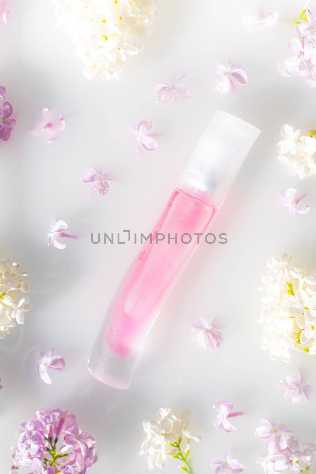 Pink perfume bottle and lilac branch on a white background. The concept of advertising perfumes. A bottle of perfume without text. Floral aromatherapy layout . Copy space