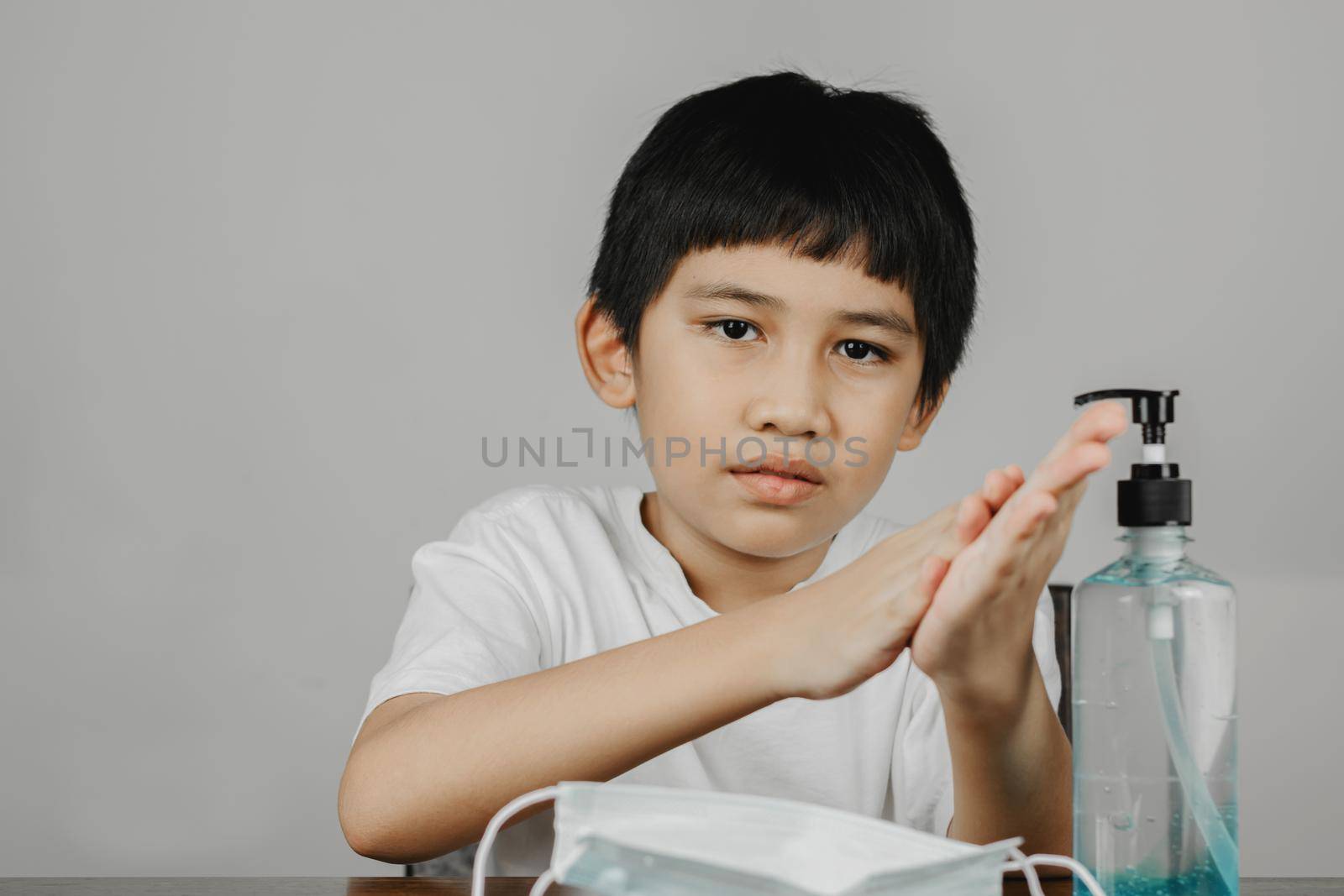 Closeup a boy face cleaning his hands with alcohol gel by wattanaphob