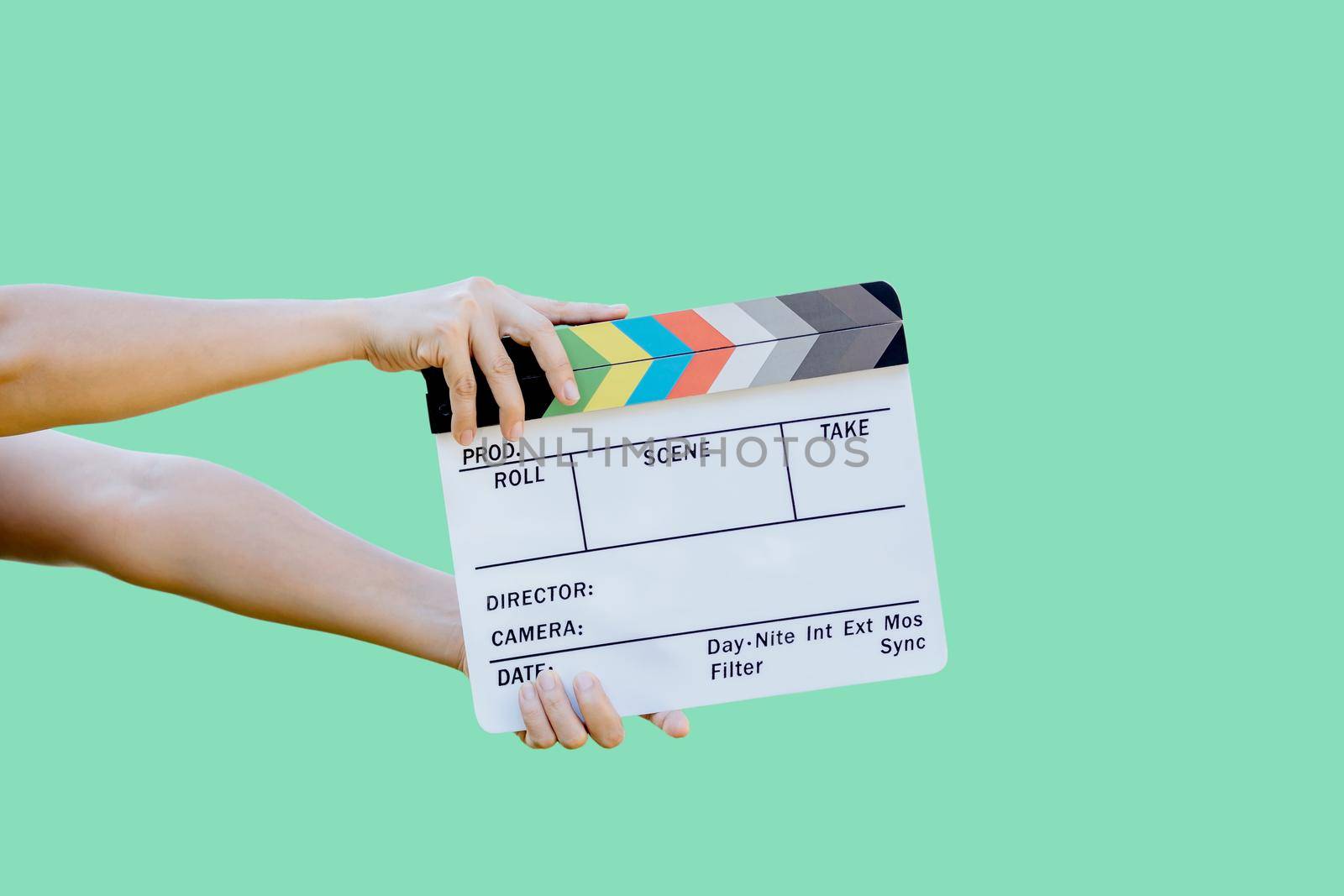Hand holding film slate colors board for movie cinema and television industry on green background by wattanaphob