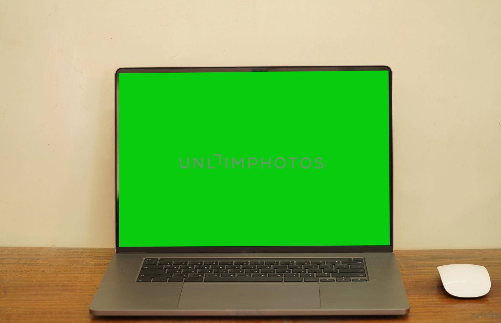 A green screen laptop and a mouse placed on a long desk. by noppha80
