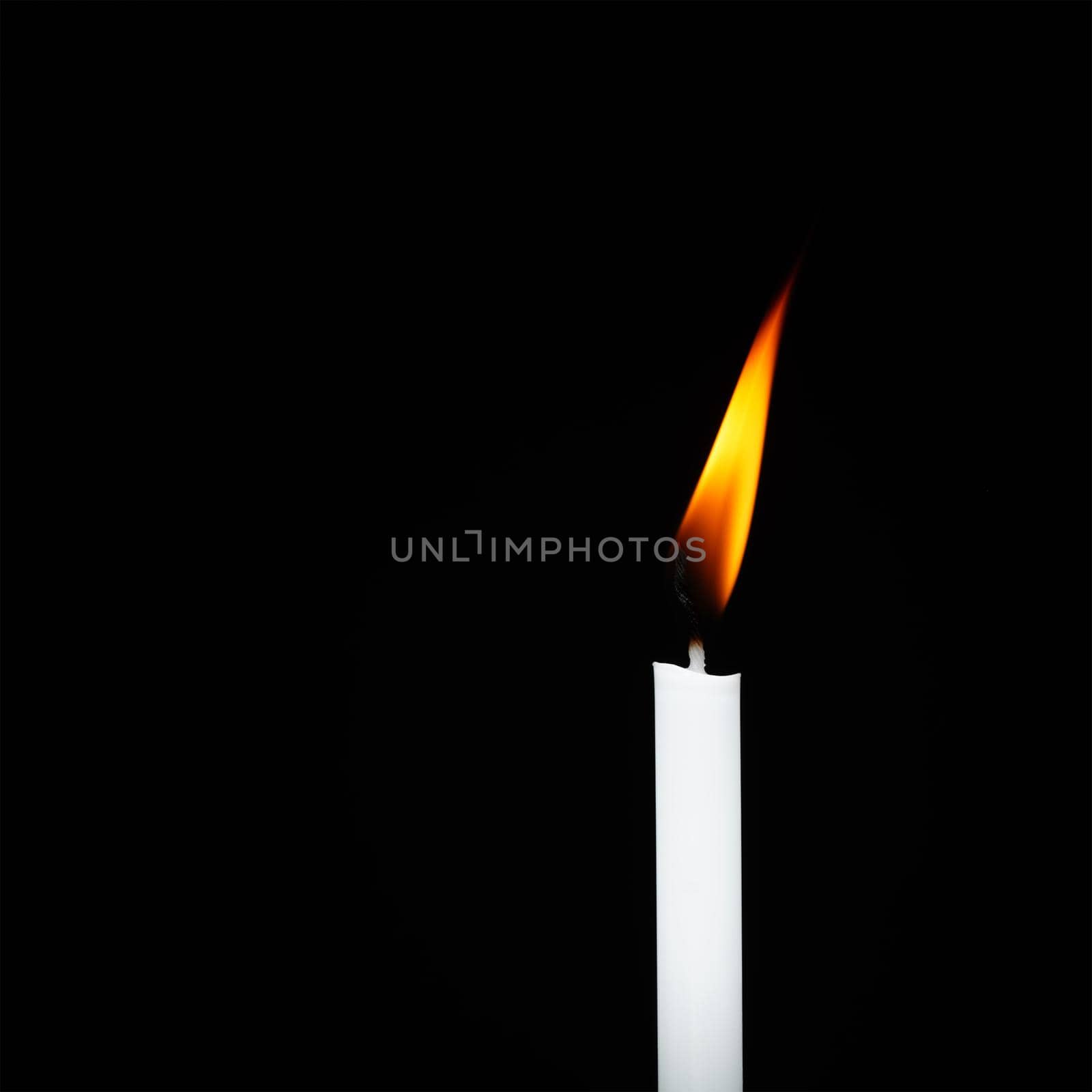 White candle flame isolated on black background religious concept belief and peace.