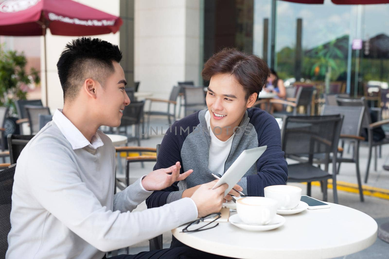 Two young handsome businessmen with tablet discussing project by makidotvn