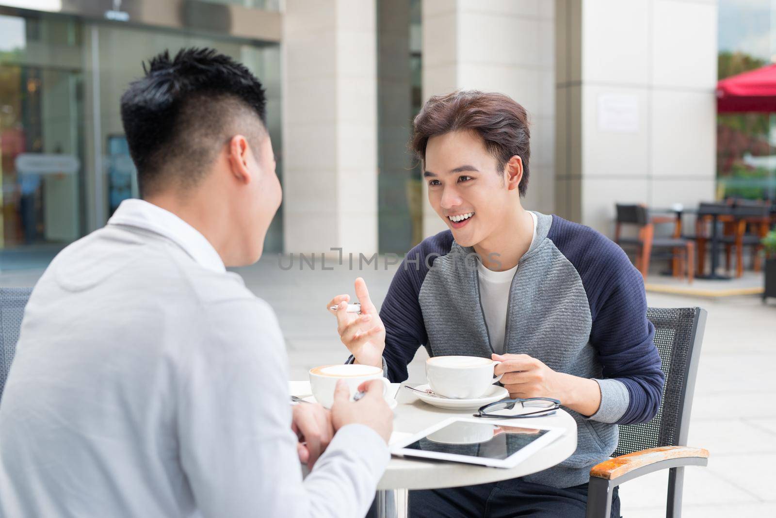 Two asian man sitting in cafe and discussing