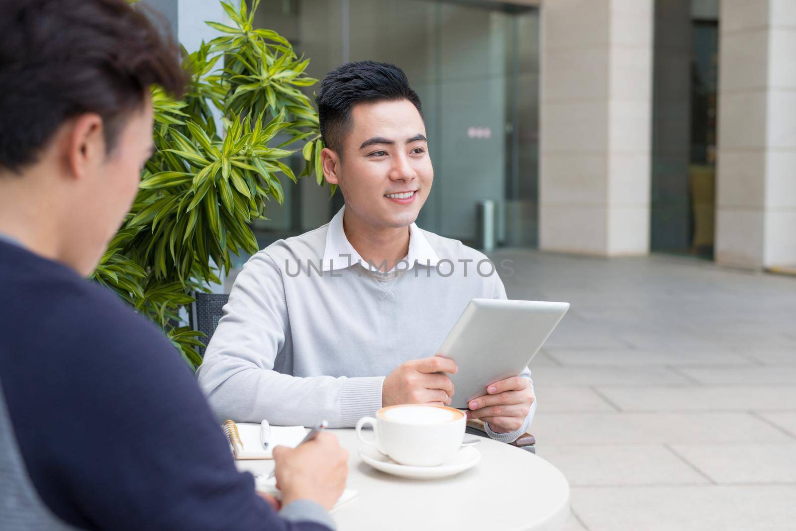 Young asian businessman thinking while his friend working