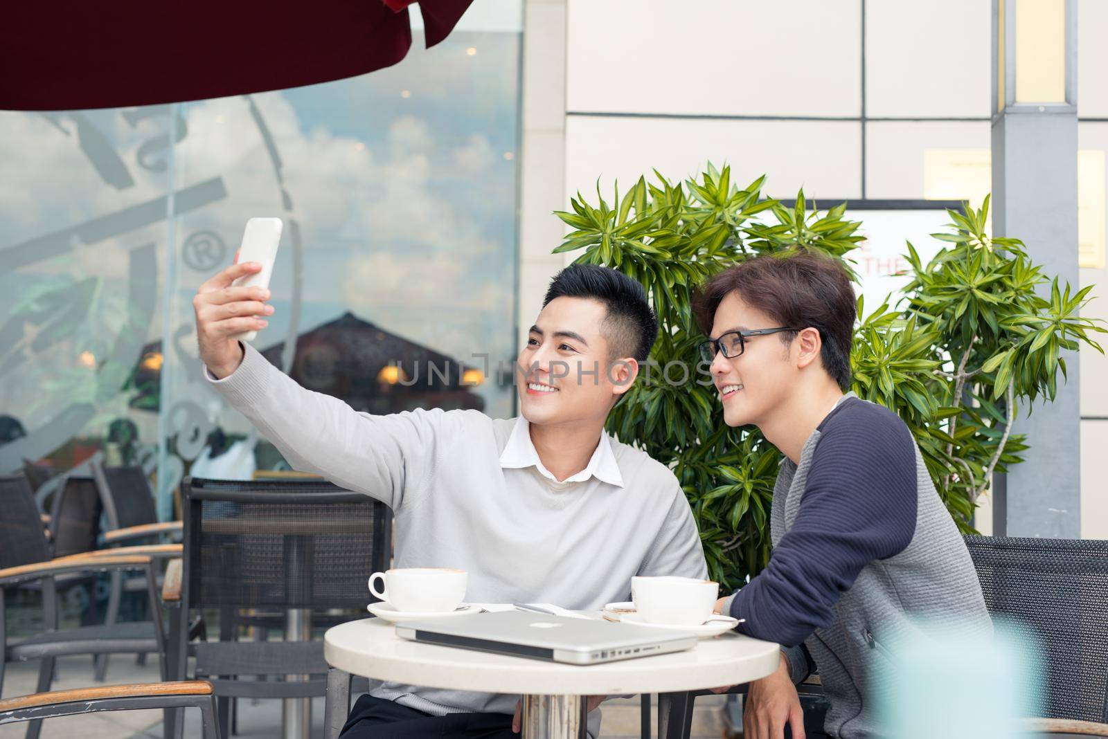 Two men are taking a selfie with a cellphone