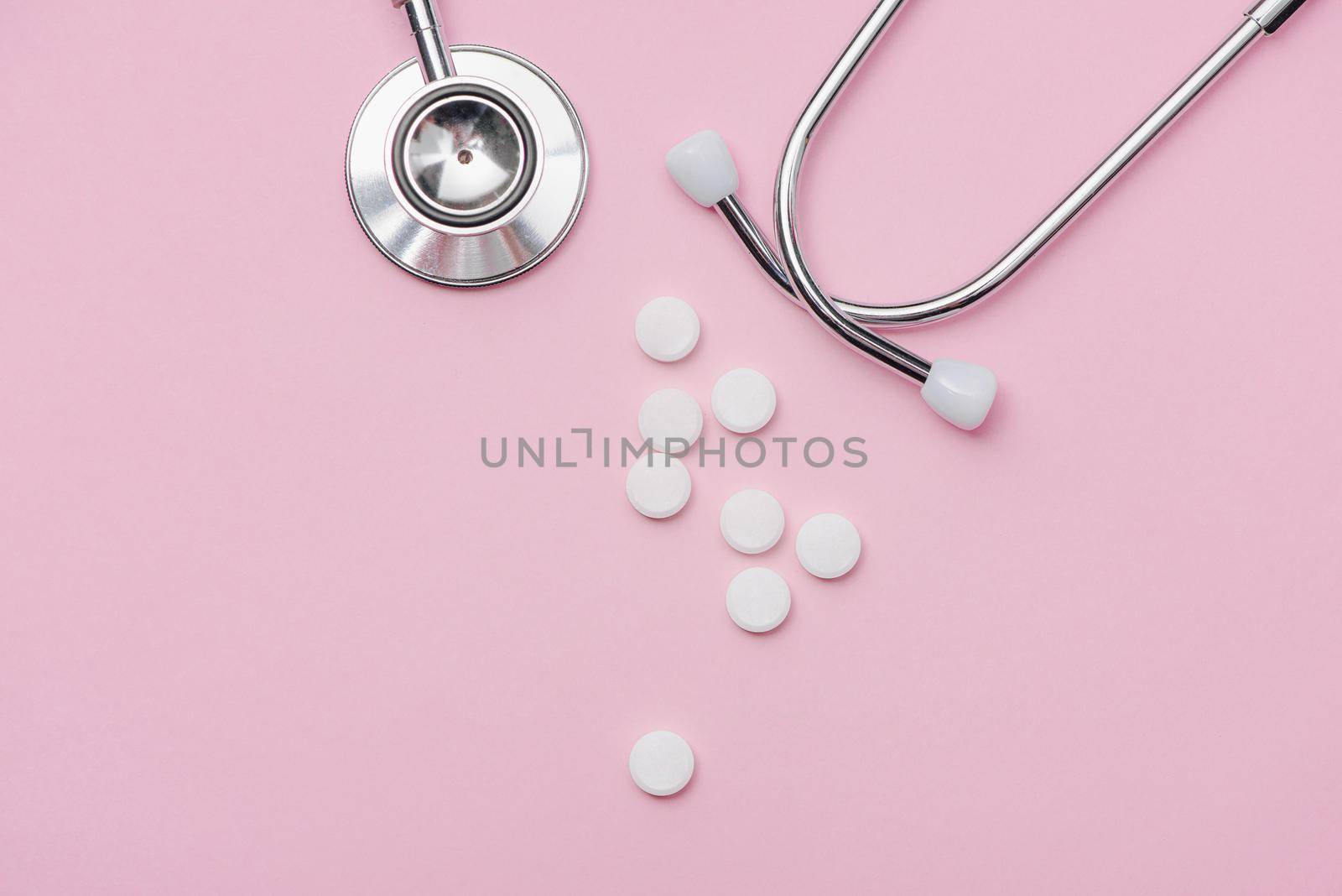Medical concept. Stethoscope and pills on pink background.