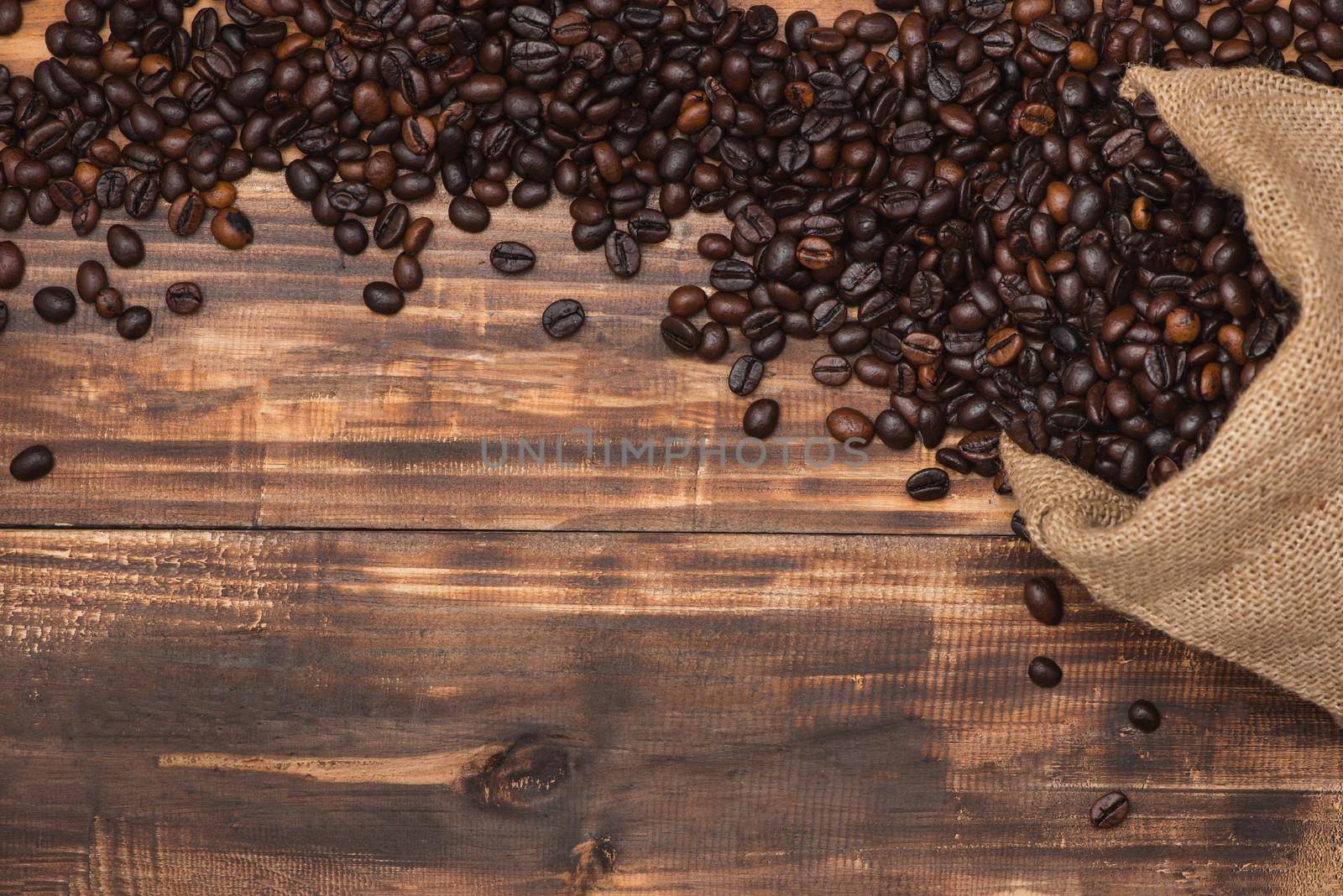 Fresh brown coffee beans on wooden background. by makidotvn