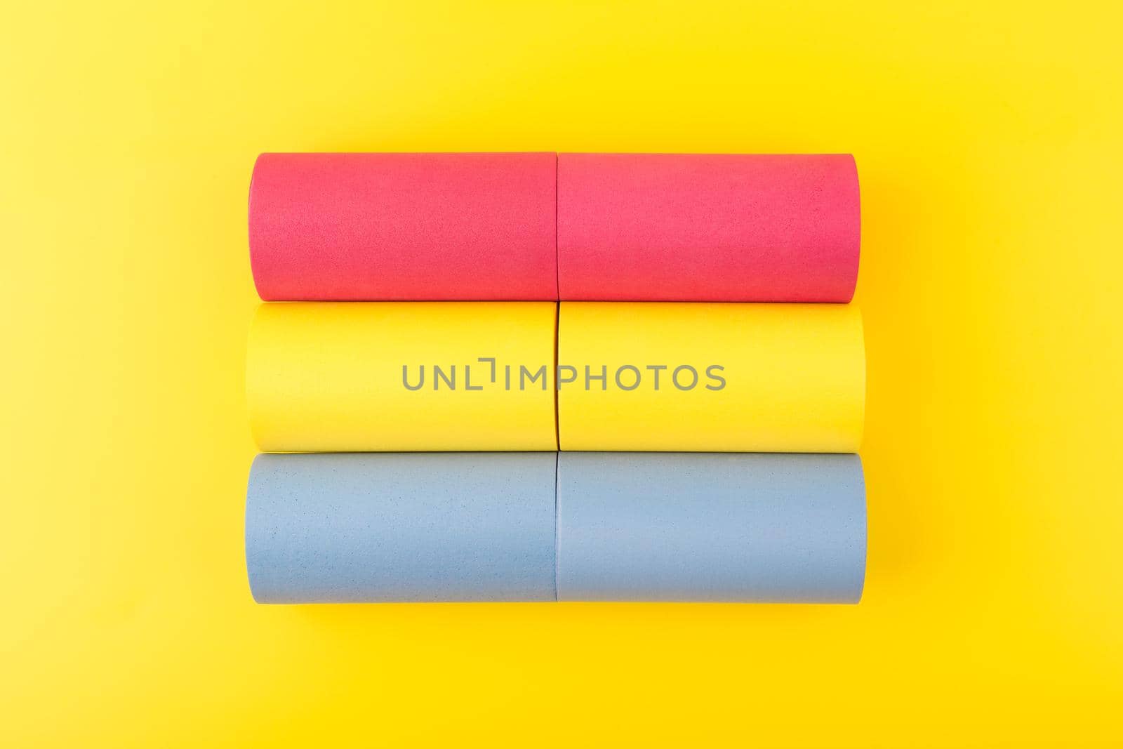 Flat lay with pansexual flag made of pink, yellow and blue rolls on yellow background. Concept of pansexual community, respect and equal rights for sexual minorities