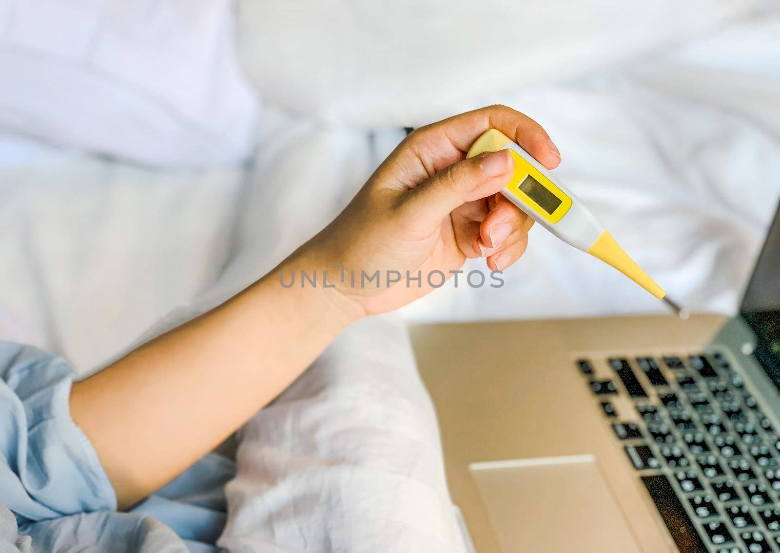Young Asian woman have a cold and high fever while checking body temperature by using digital thermometer by Benzoix