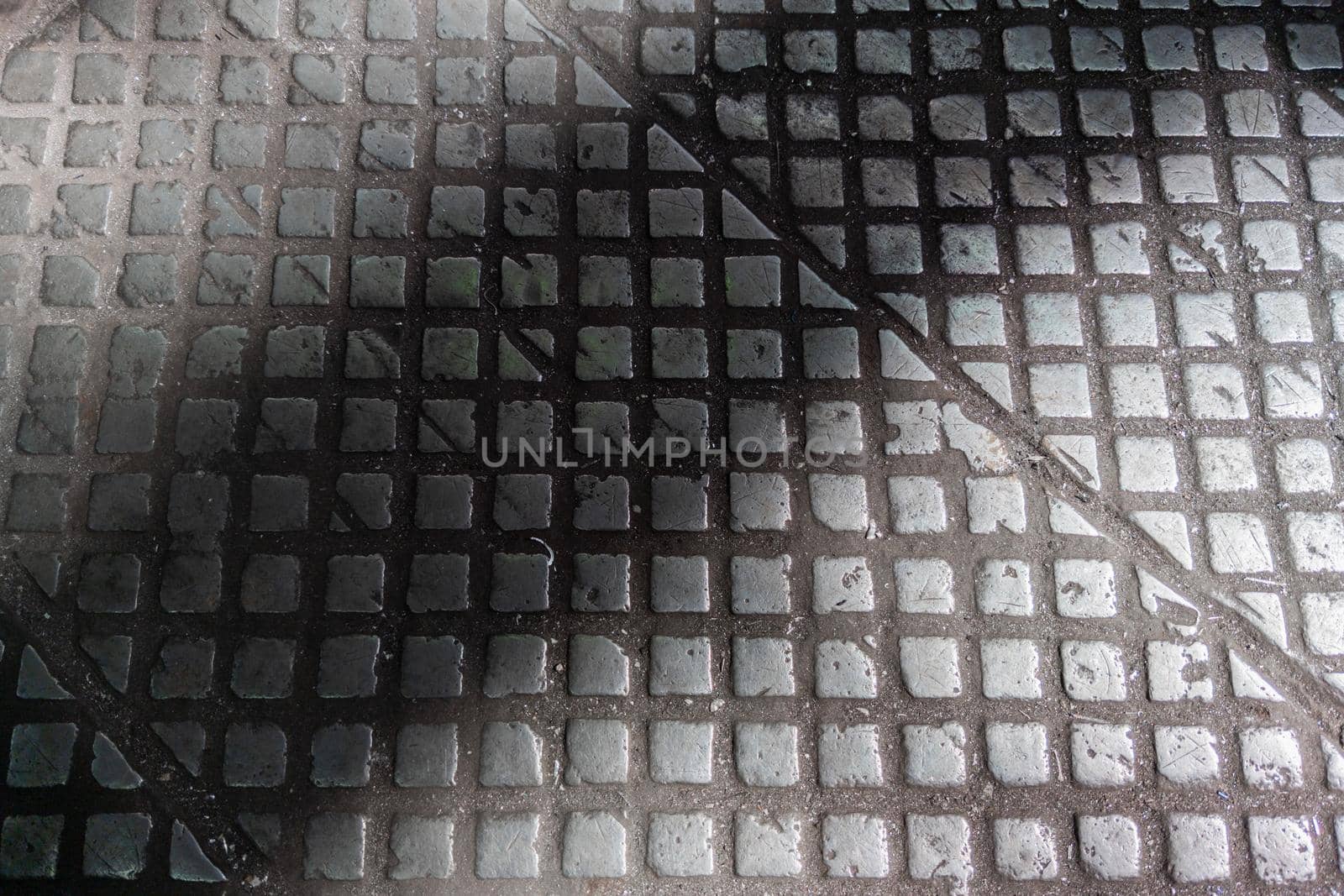 old cast iron industrial floor tiles with checkered skid-proof pattern - factory background.