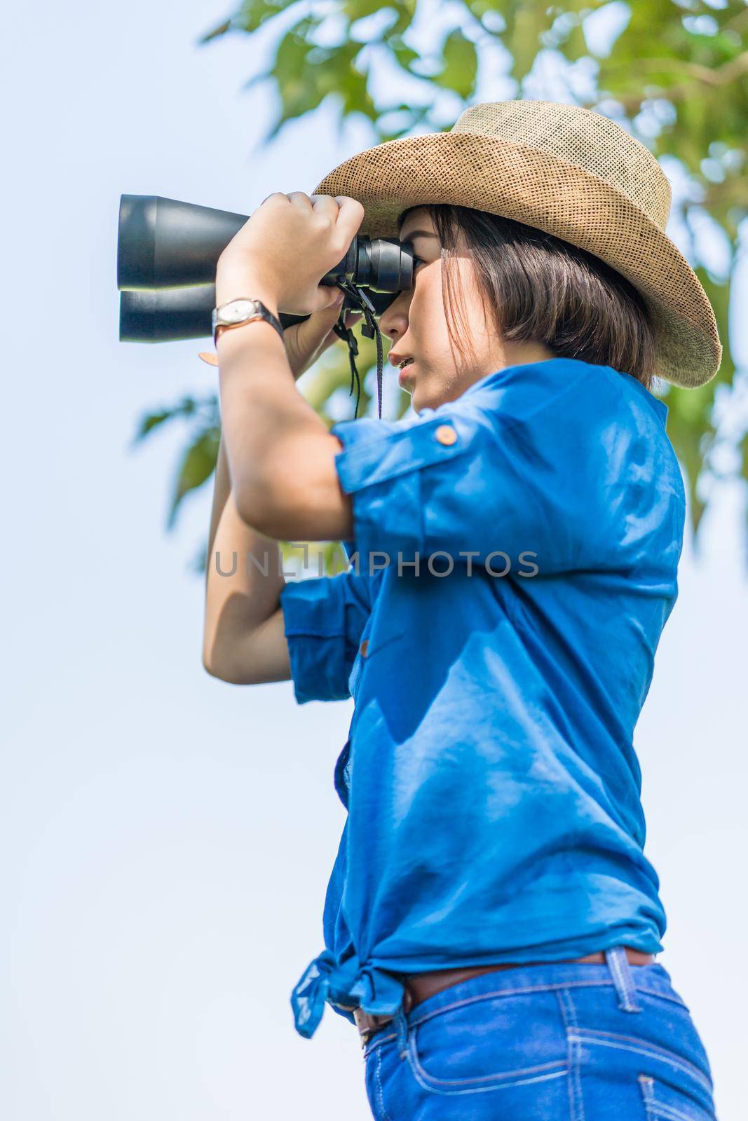 Close up Young asian woman short hair wear hat and hold binocular in grass field countryside Thailand