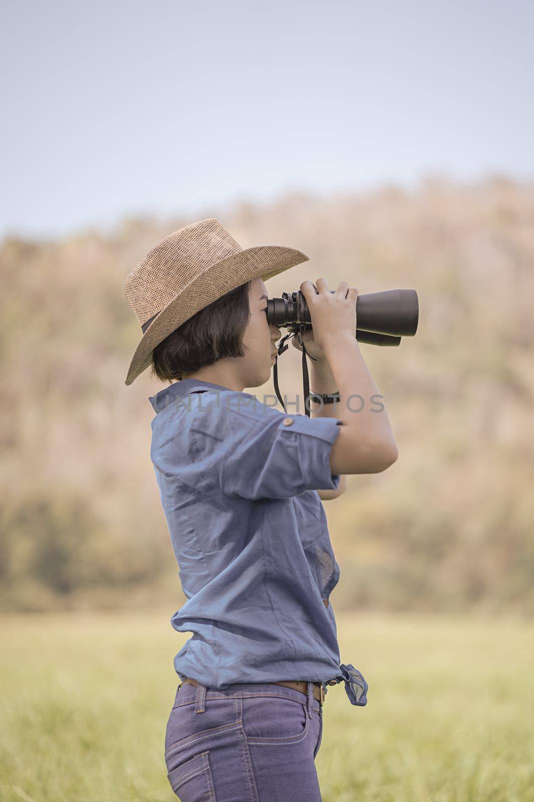 Woman wear hat and hold binocular in grass field by stoonn