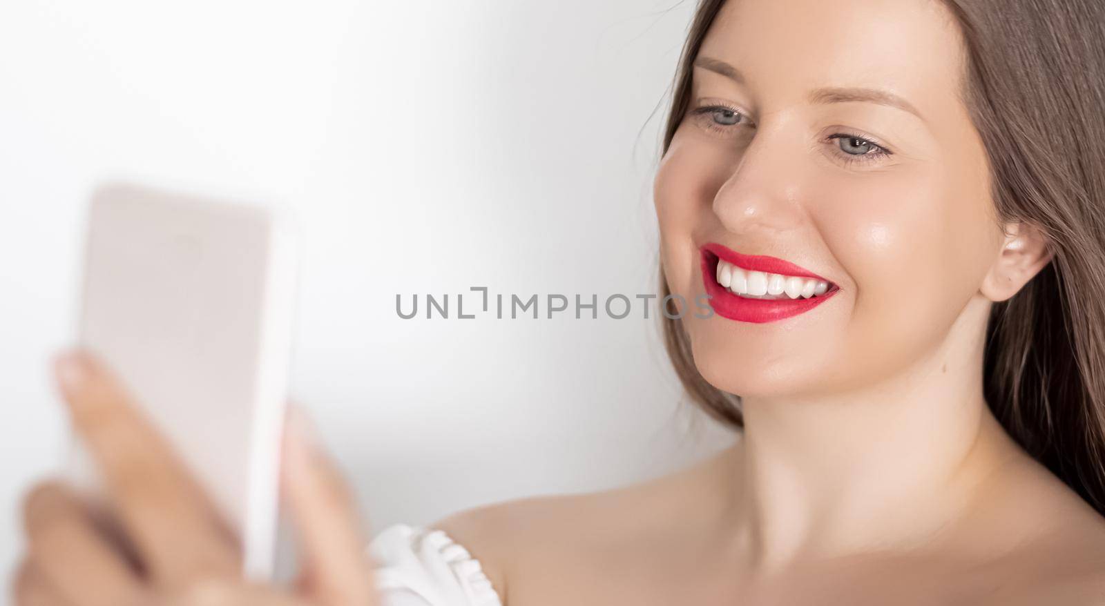 Happy smiling woman with smartphone having video call or taking selfie, portrait on white background. People, technology and communication concept by Anneleven