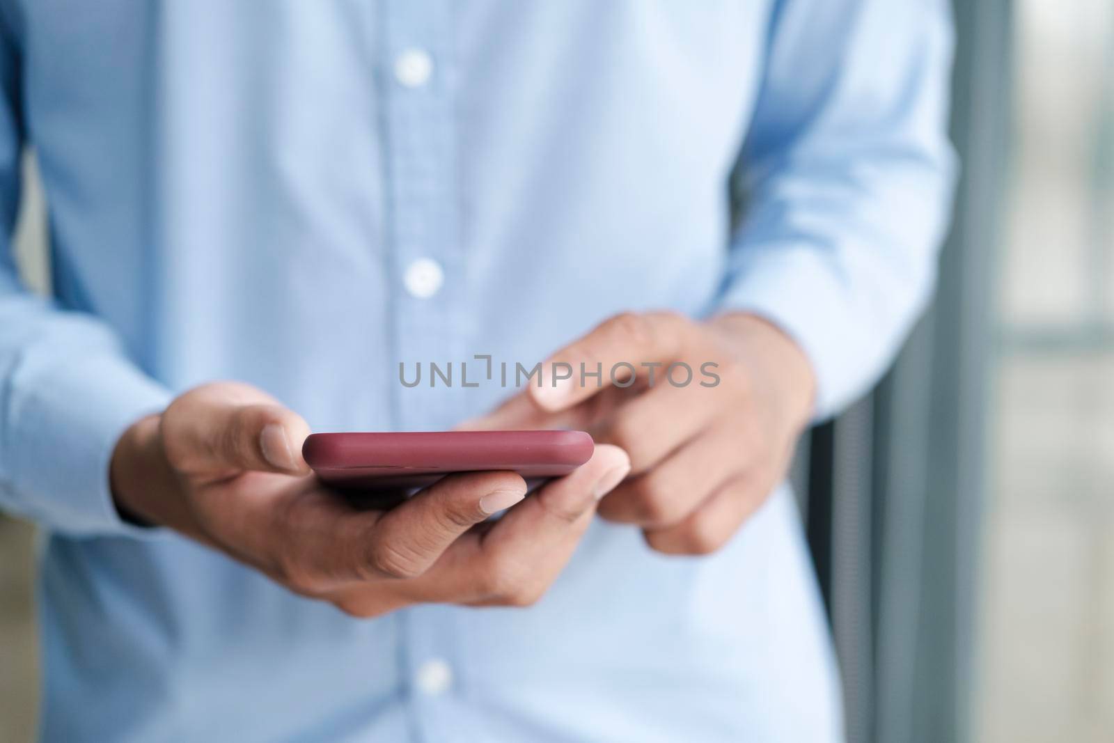 Close up shot of man's hands holding mobile phone while using wireless high-speed Internet connection.