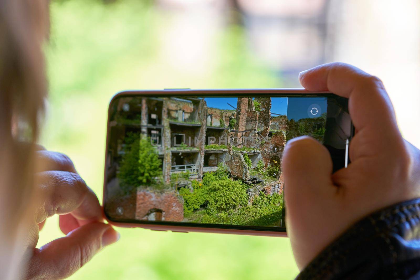 Hand holds mobile phone taking pictures of the old fortress. Taking a photo on smartphone while traveling. Fortress Oreshek