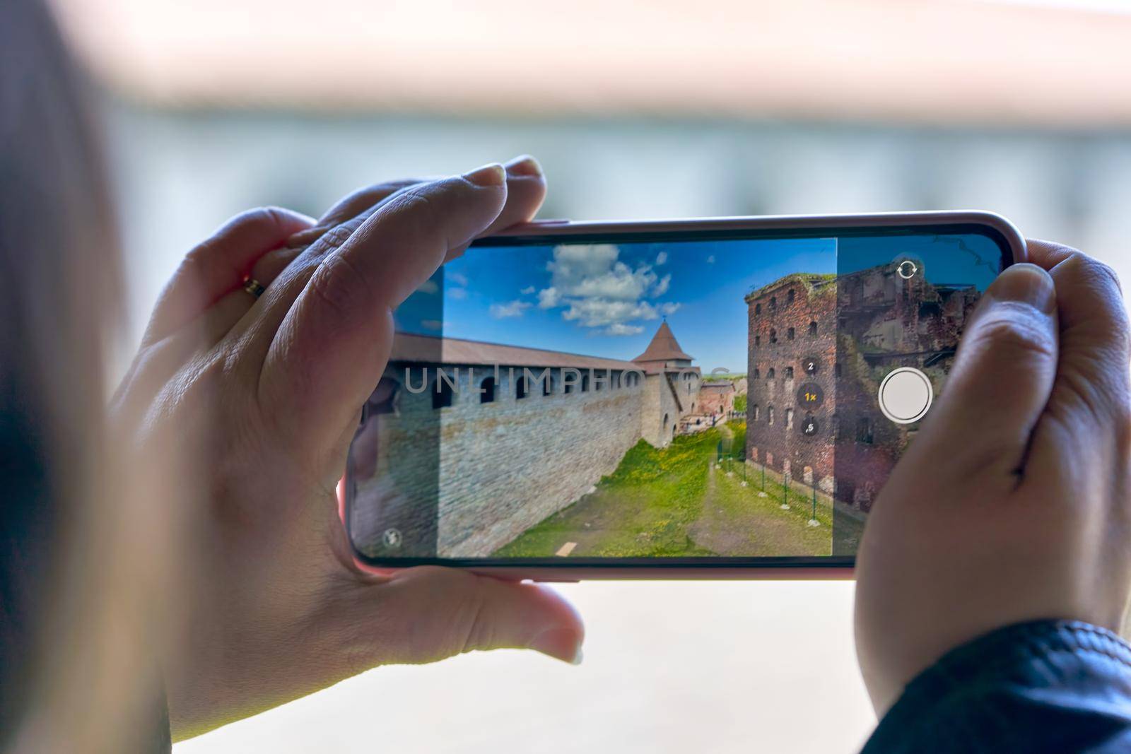 Hand holds mobile phone taking pictures of the old fortress. Taking a photo on smartphone while traveling. Fortress Oreshek