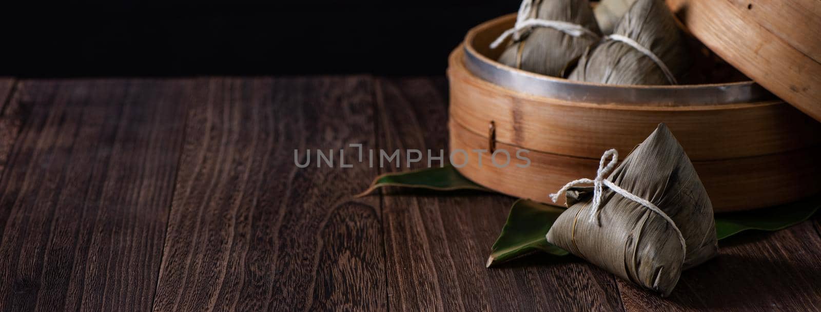 Zongzi. Rice dumpling for Chinese traditional Dragon Boat Festival (Duanwu Festival) on dark wooden table background.