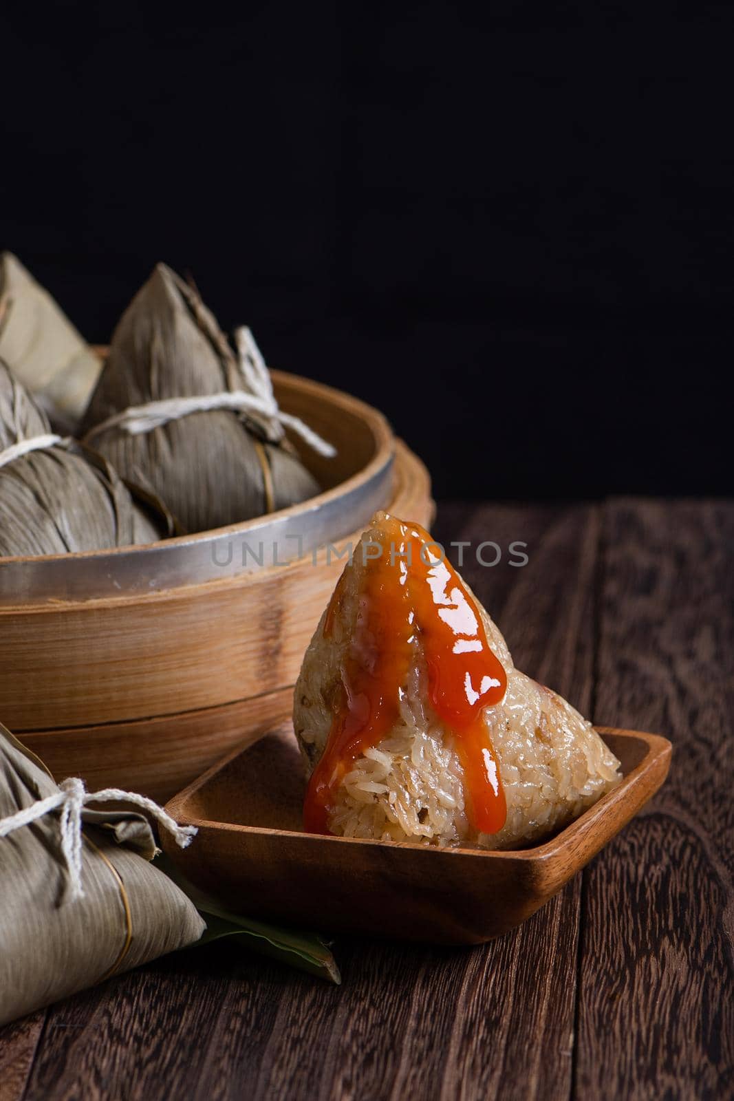 Zongzi. Rice dumpling for Chinese traditional Dragon Boat Festival (Duanwu Festival) on dark wooden table background.