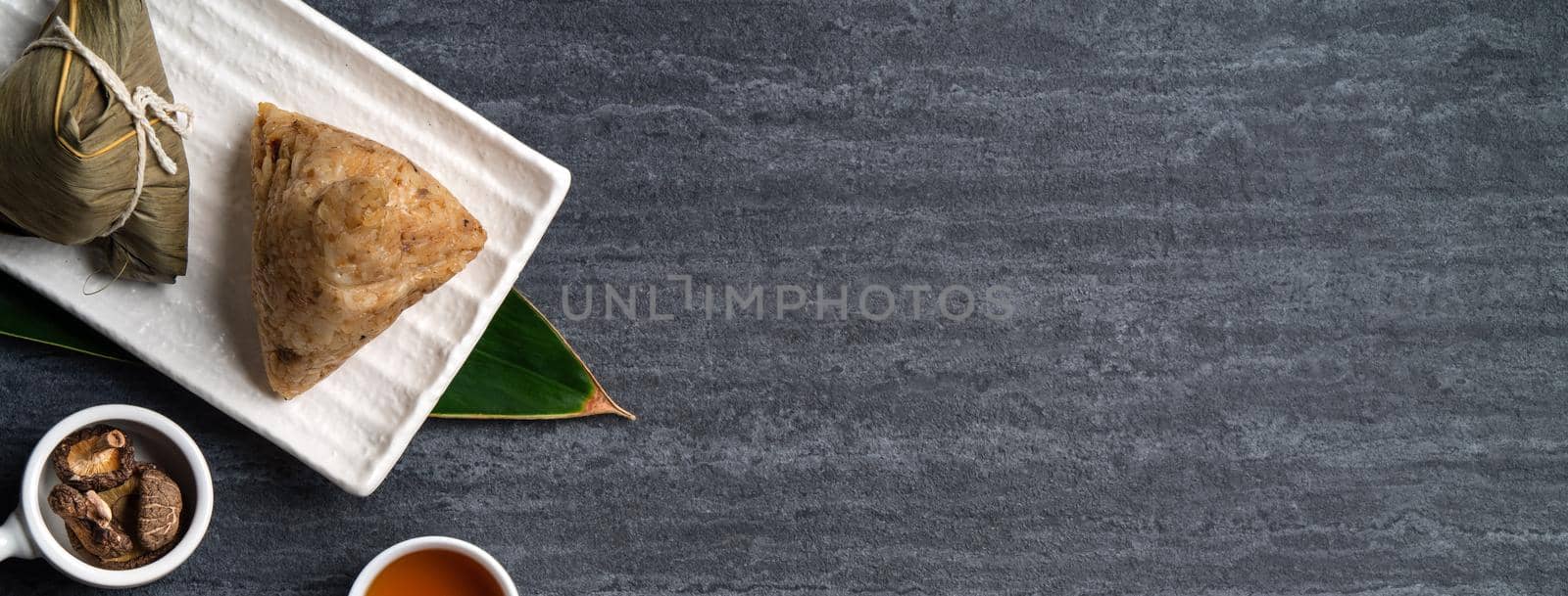 Zongzi. Rice dumpling top view design concept for Chinese traditional Dragon Boat Festival (Duanwu Festival) over dark black slate background.