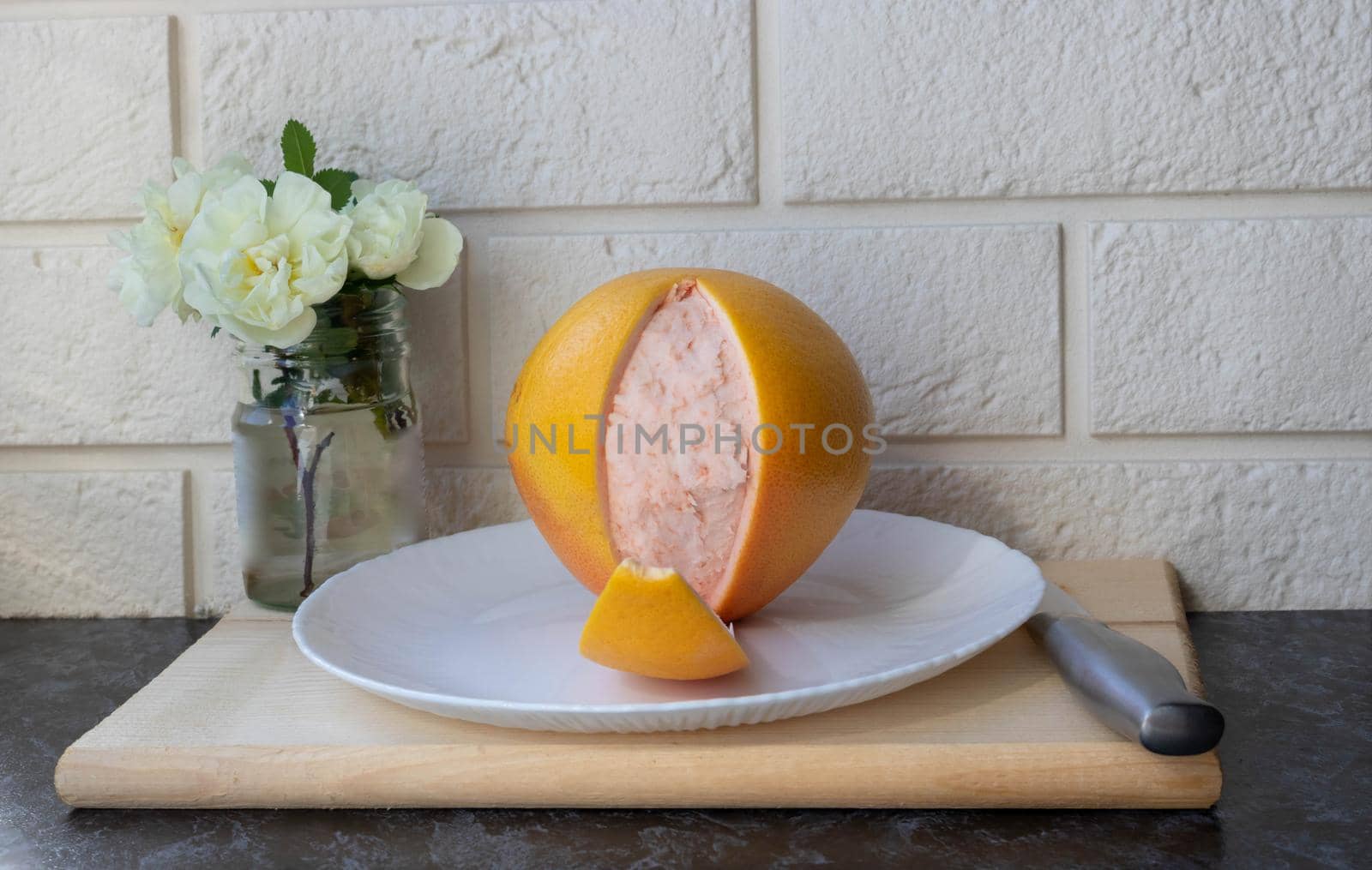 Fresh healthy grapefruit on a white plate on the kitchen table. Creative concept of minimal food. Grapefruit slices of citrus.