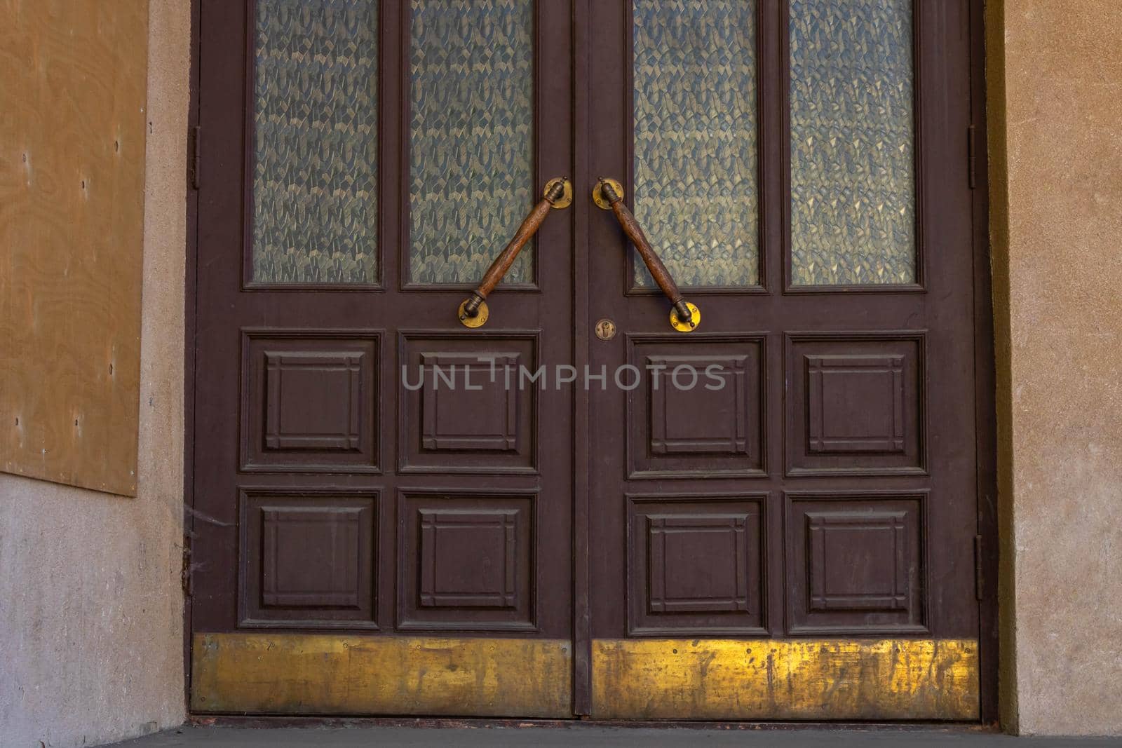 Antique door handles on a brown wooden door with fluted panes.