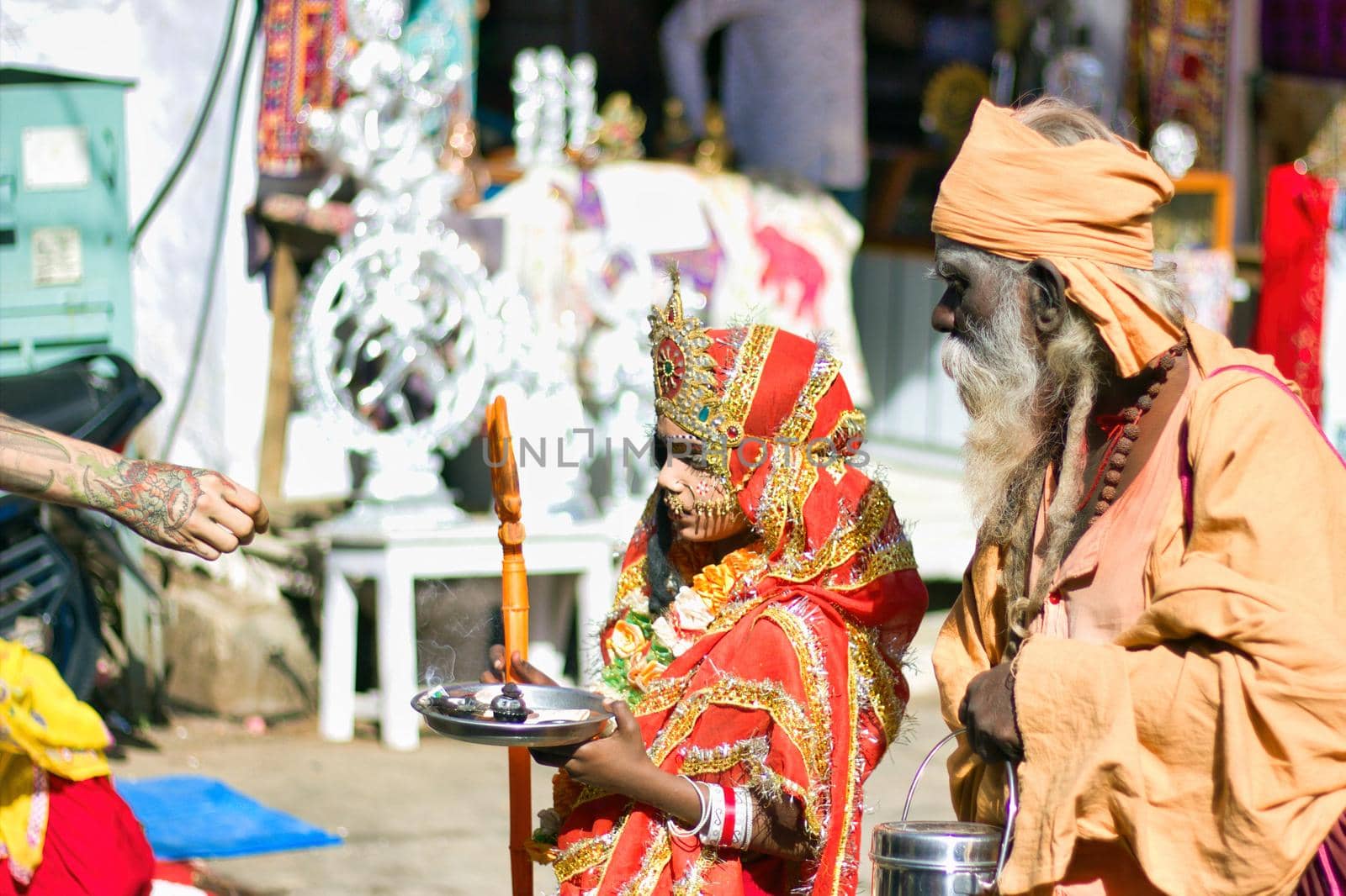 Pushkar, India - November 10, 2016: A young little girl dressed up or disguised as Indian goddess with crown, red dress and trishul to attract tourist getting money as street performer in famous fair