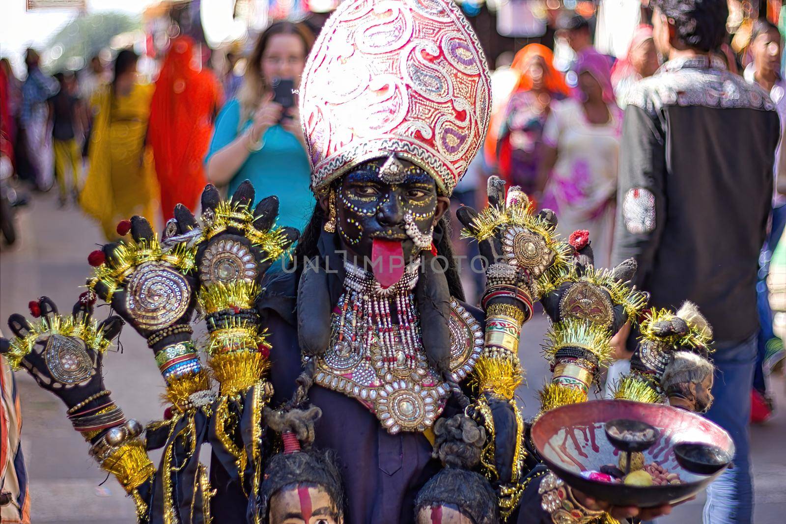 Pushkar, India - November 10, 2016: A young little girl dressed up or disguised as Indian goddess of destruction named maa Kali with crown and multiple hands as street performer during Pushkar fair by arpanbhatia