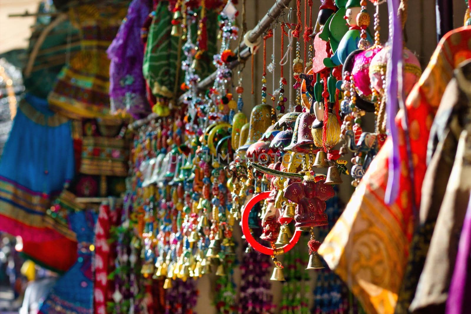 Bunch of colorful decorative item as souvenir being hanging as display for sale in the commercial street of pushkar fair in the state of Rajasthan