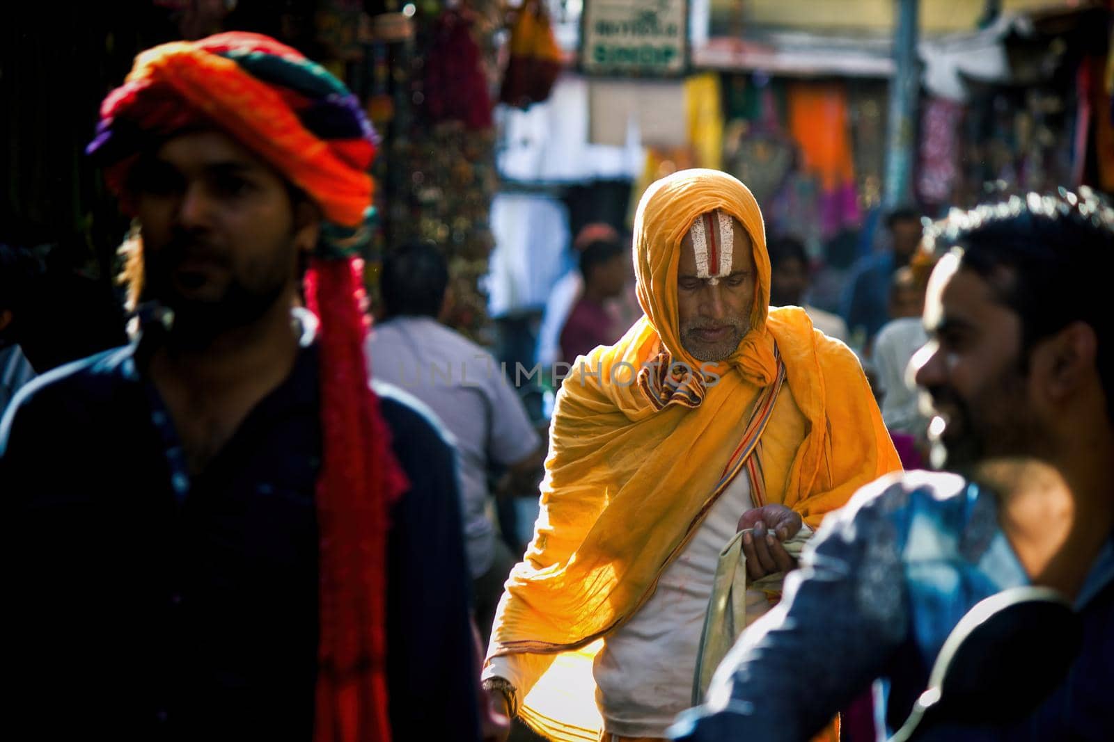 Pushkar, India - November 10, 2016: A hindu man with vishnu tilak on his forehead and orange ethnic wear walking in famous pushkar mela or fair in the state of Rajasthan by arpanbhatia