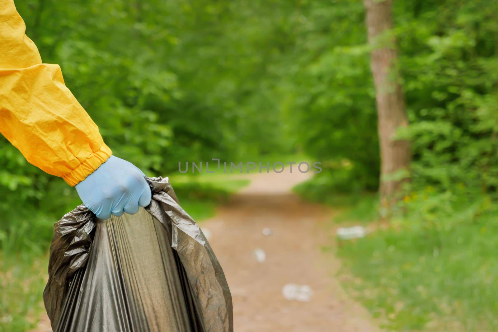 Volunteer cleaning up garbage a park. People care earth pollution plastic garbage worker hand holding trash bag. Volunteer hands picks up a plastic trash grass in park. Eco friendly background forest by synel