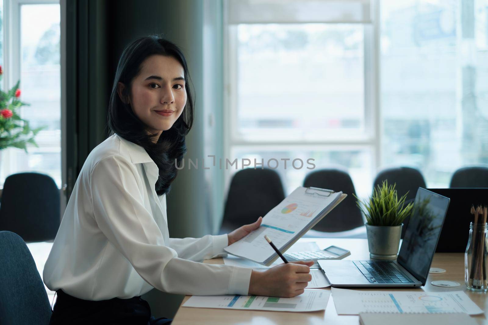 Portrait of a smiling entrepreneur or accountant while working with paperwork in office at her corporate