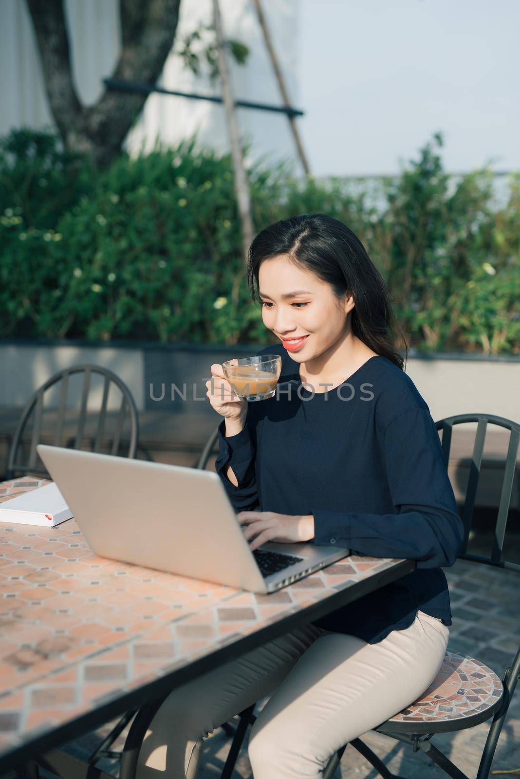 Taking advantages of free Wi-Fi. Beautiful young woman working on laptop and smiling while sitting outdoors