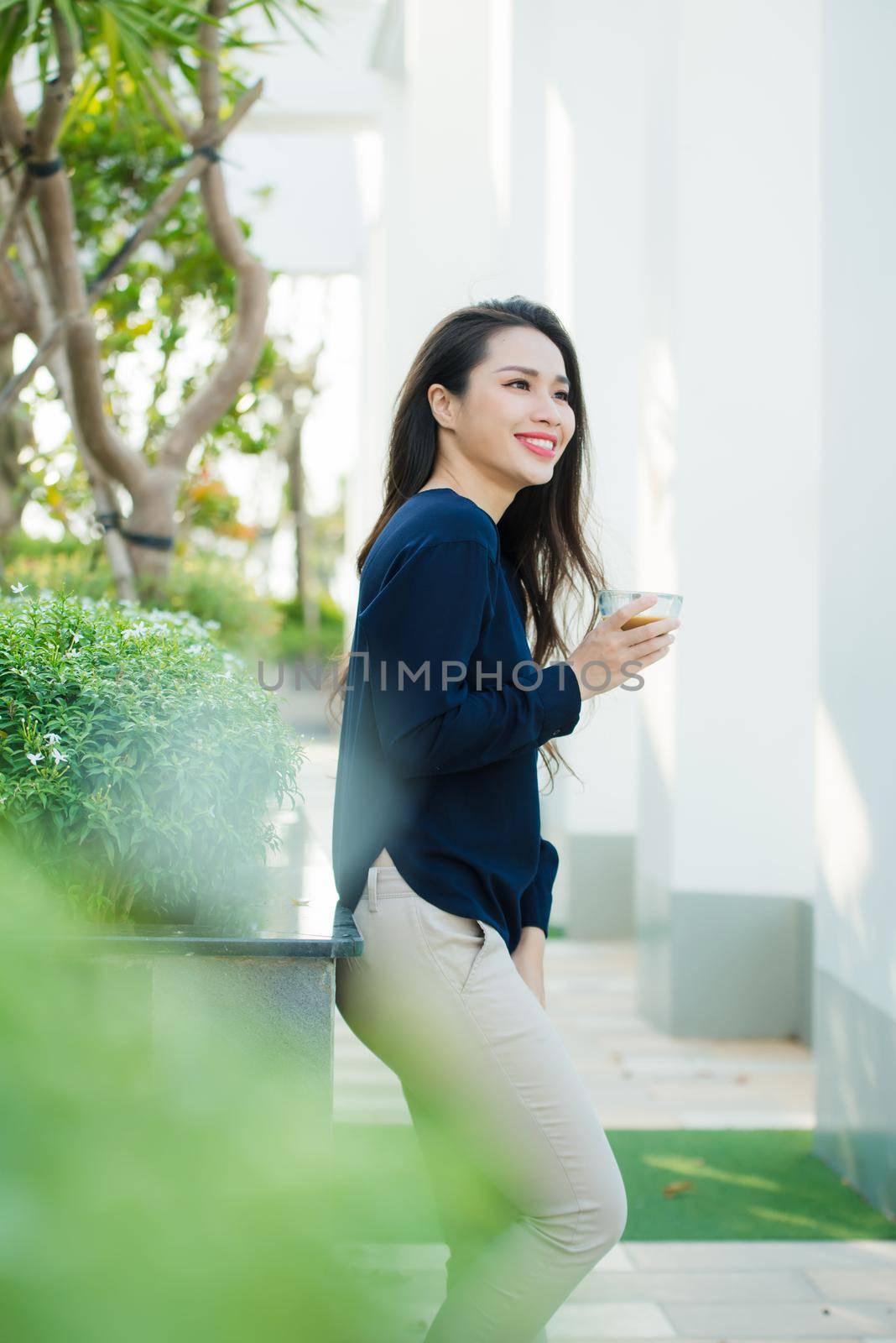 Summer terrace. Woman feeling very relaxed with hand holding glass of coffee while standing on summer terrace 
