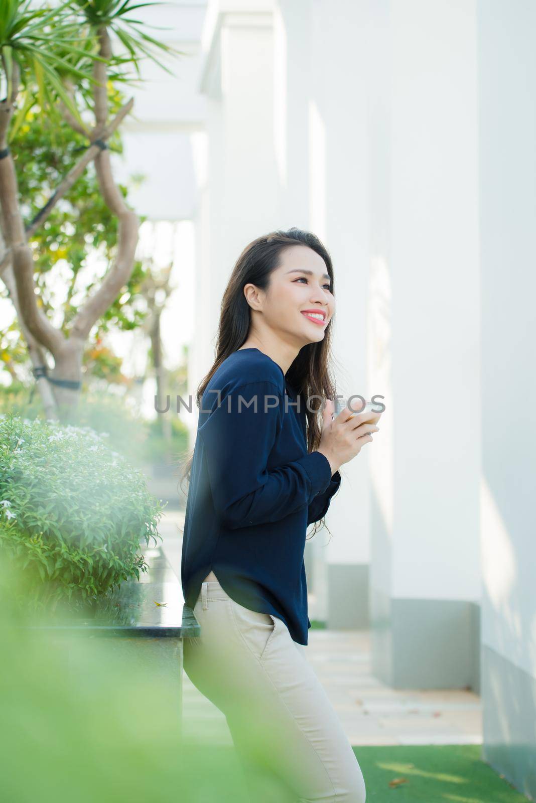Summer terrace. Woman feeling very relaxed with hand holding glass of coffee while standing on summer terrace 