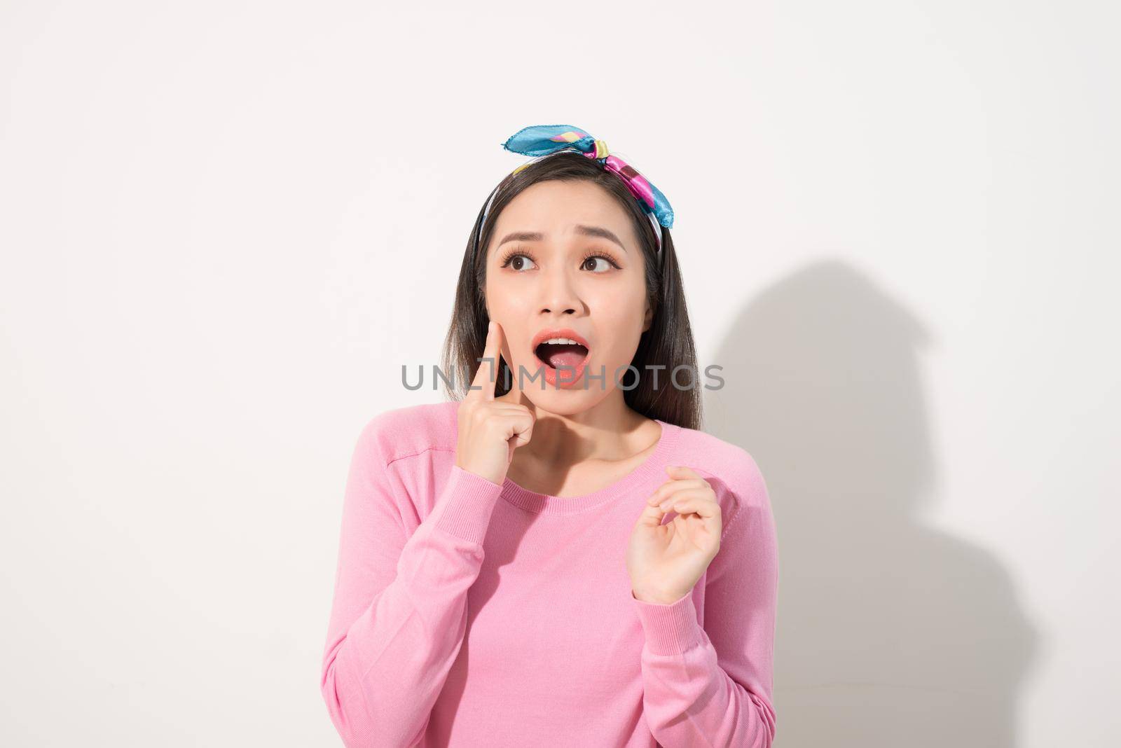 Young beautiful Asian woman scared of sunshine isolated over white background. Concept for summer skin care and skin protection from uv sunshine