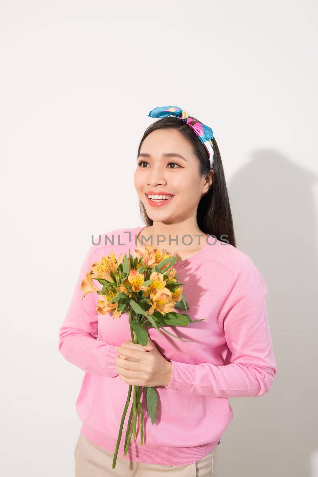 Toothy smiling happy woman holding flower . White background isolated portrait.