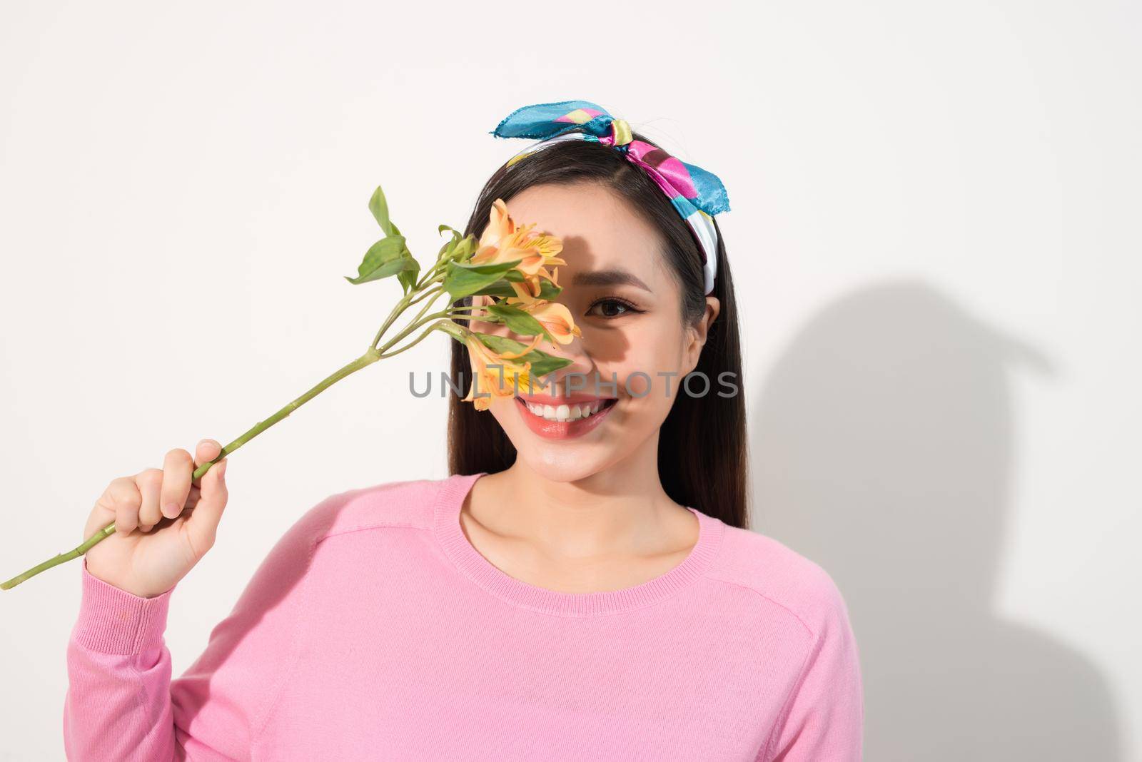 Young woman covering her eye with fresh colorful flowers. Enjoying spring time