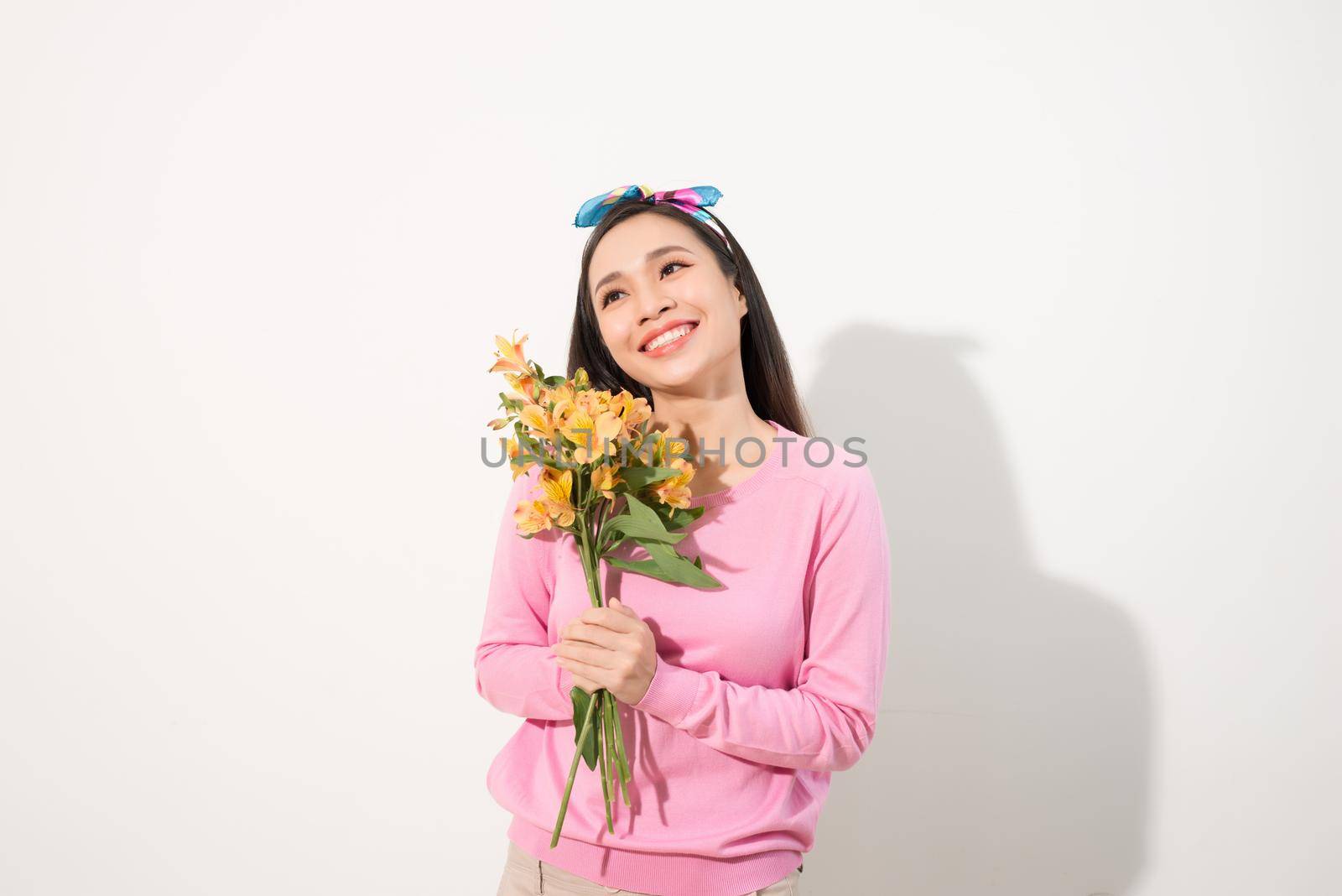 Beautiful girl in the pink dress with flowers in hands on a white background