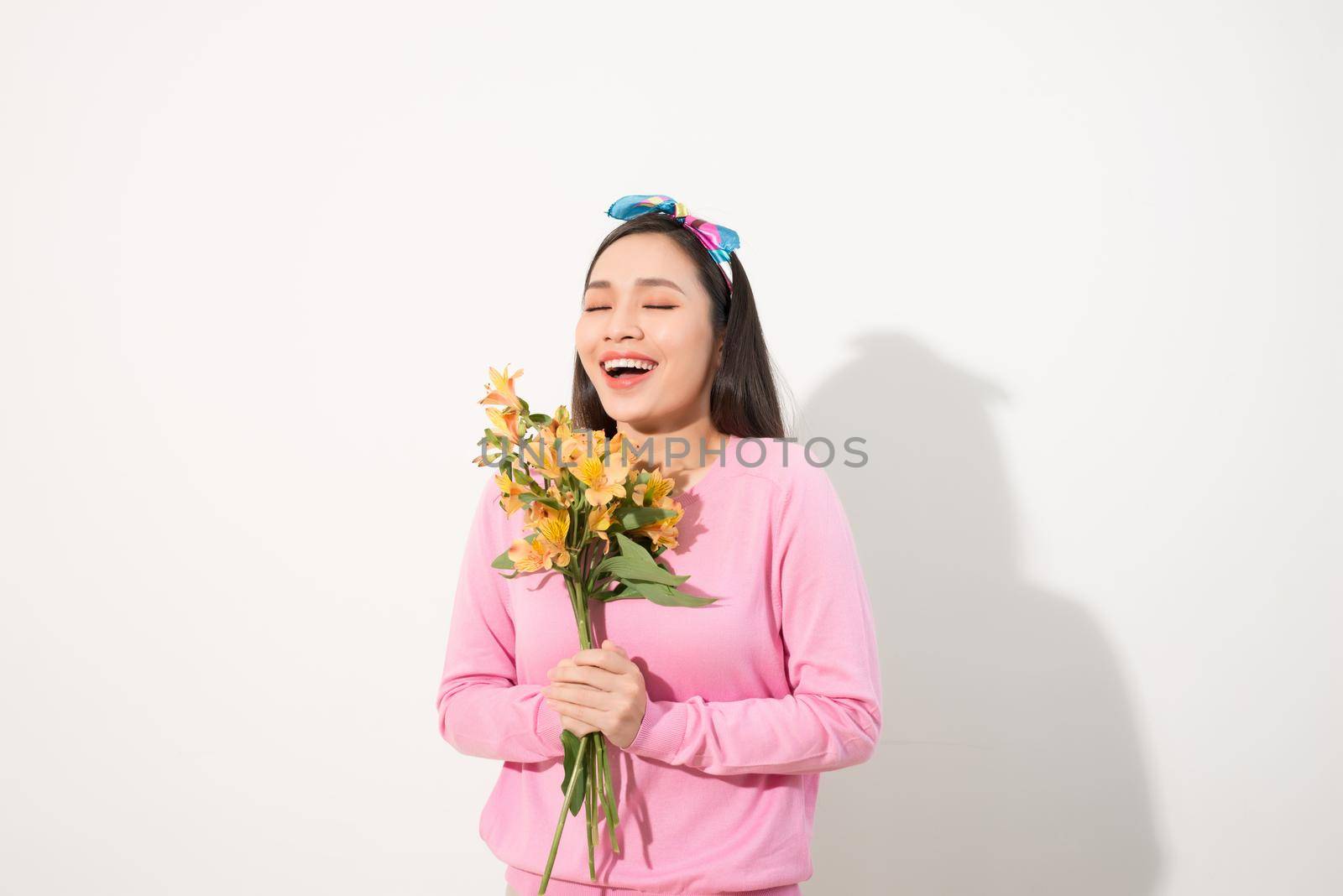 Beautiful girl in the pink dress with flowers in hands on a white background by makidotvn