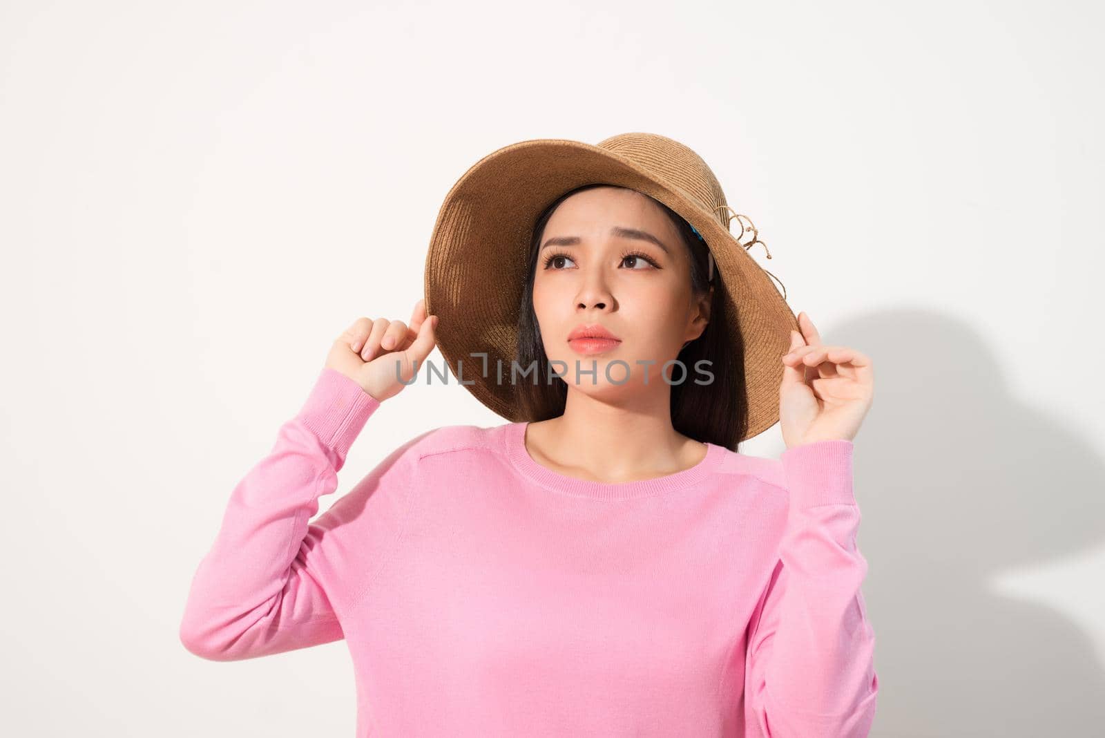 Closeup of sad pensive young woman and straw hat thinking and feeling unhappy over white background by makidotvn