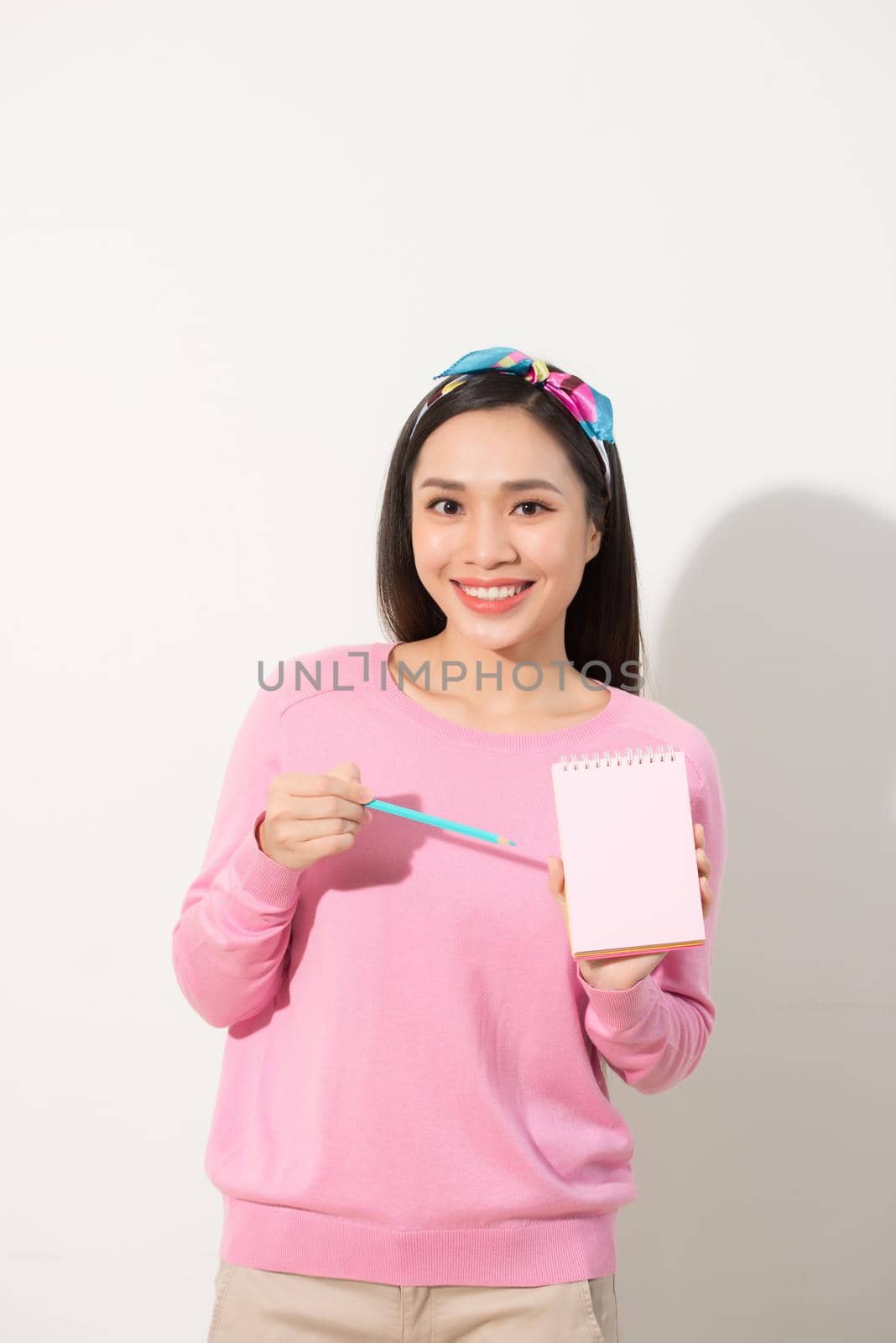 Closeup image of a beautiful Asian woman holding and showing blank notebook  by makidotvn